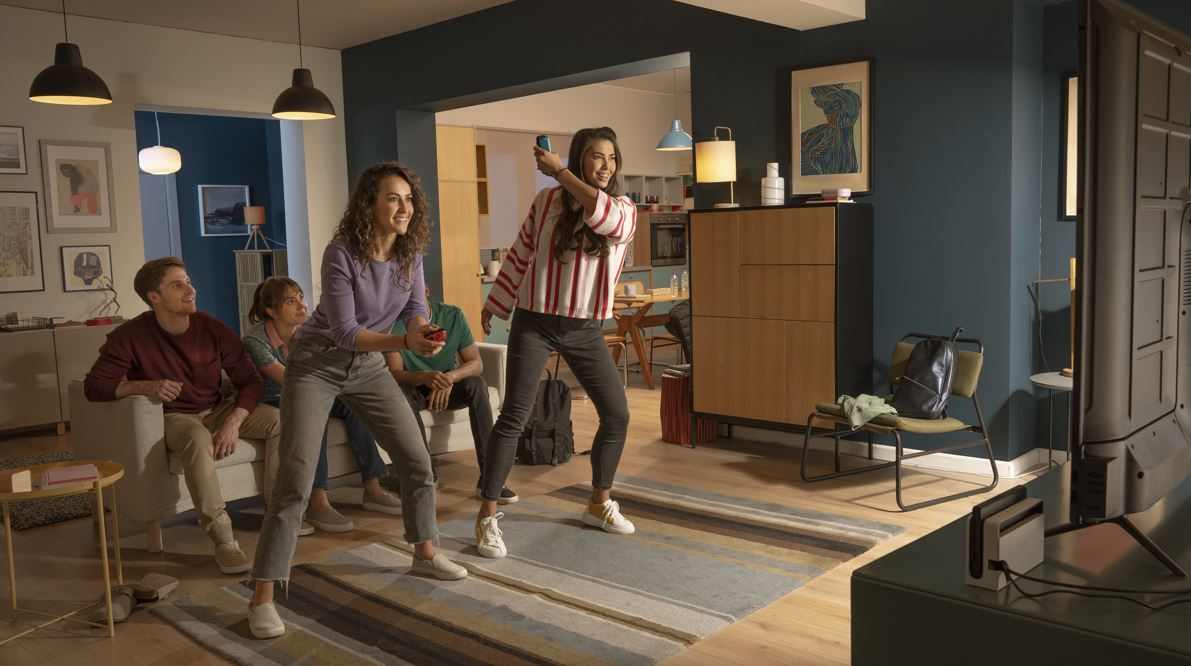 Group of people playing video games in a living room. They are using controllers.
