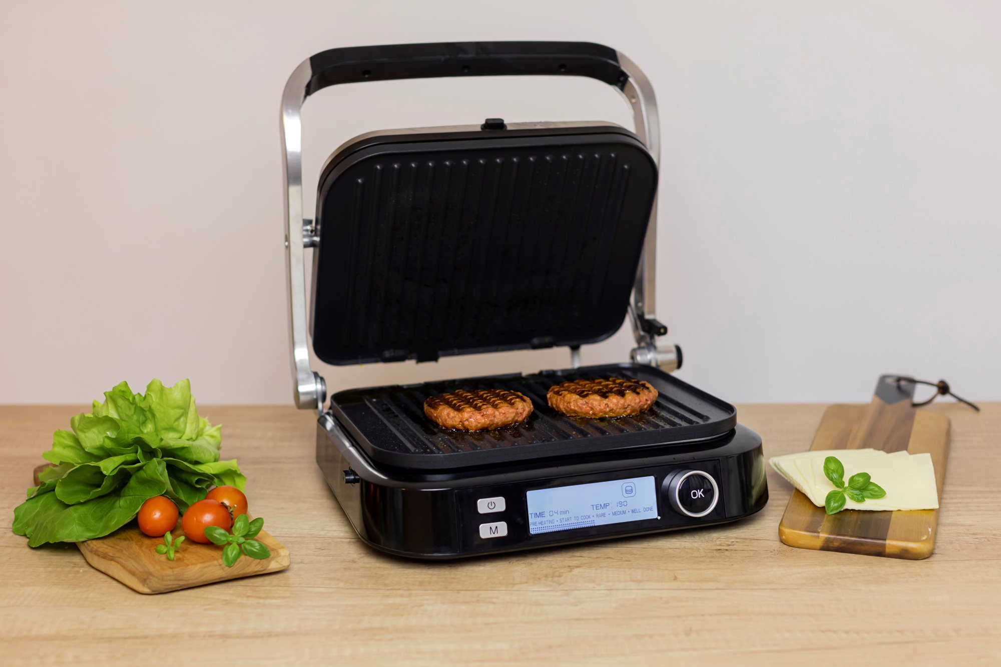 Nyitott grill hamburgerekkel, hozzávalókkal, fa deszkával.