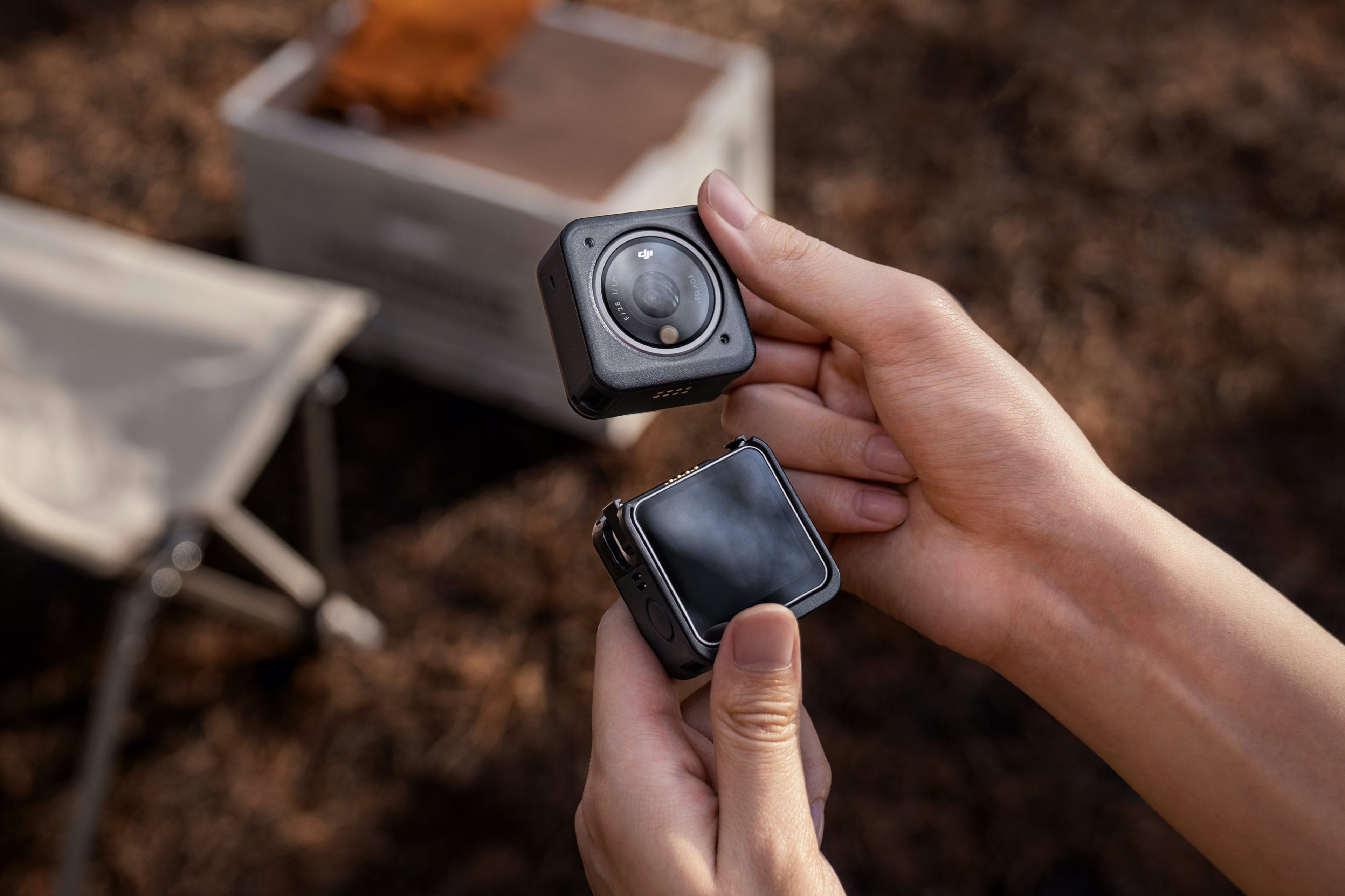 Deux mains tenant deux caméras DJI Osmo Action noires, une proche, une flottant au-dessus.