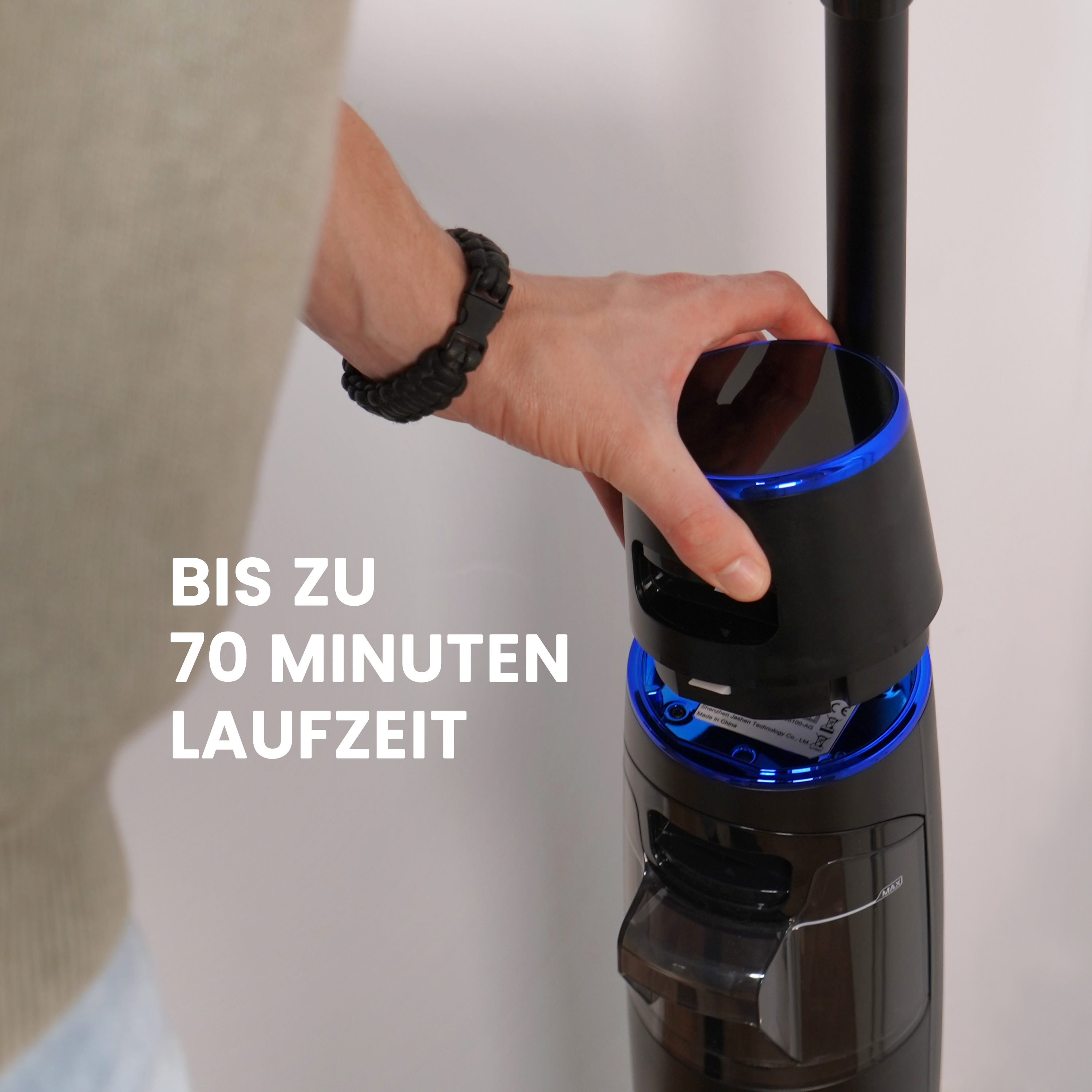 Person befestigt einen schwarz-blauen Staubsaugerteil. Text: 70 Minuten.