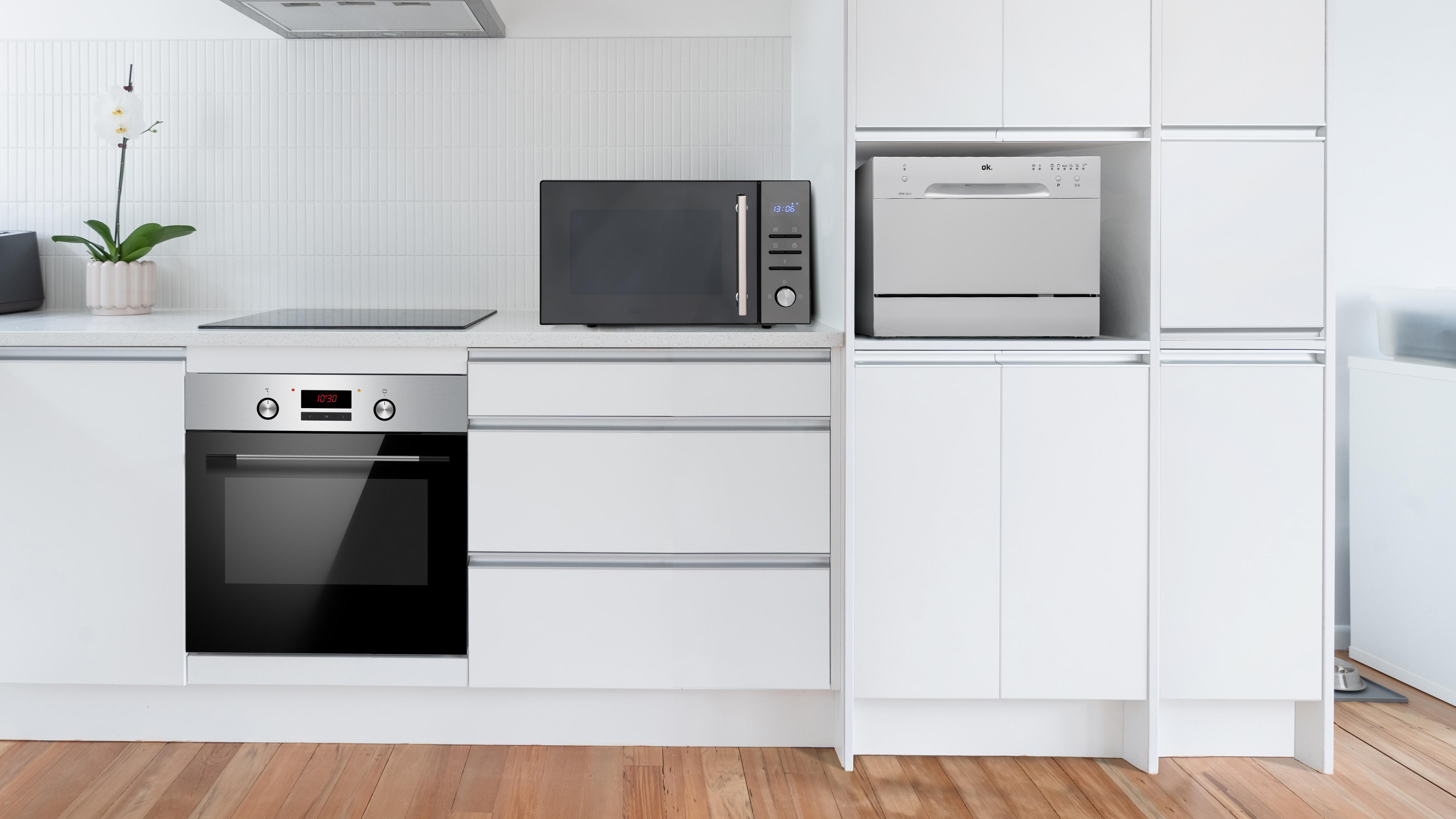 Moderne weiße Küche mit Geräten: Backofen, Mikrowelle und Geschirrspüler.