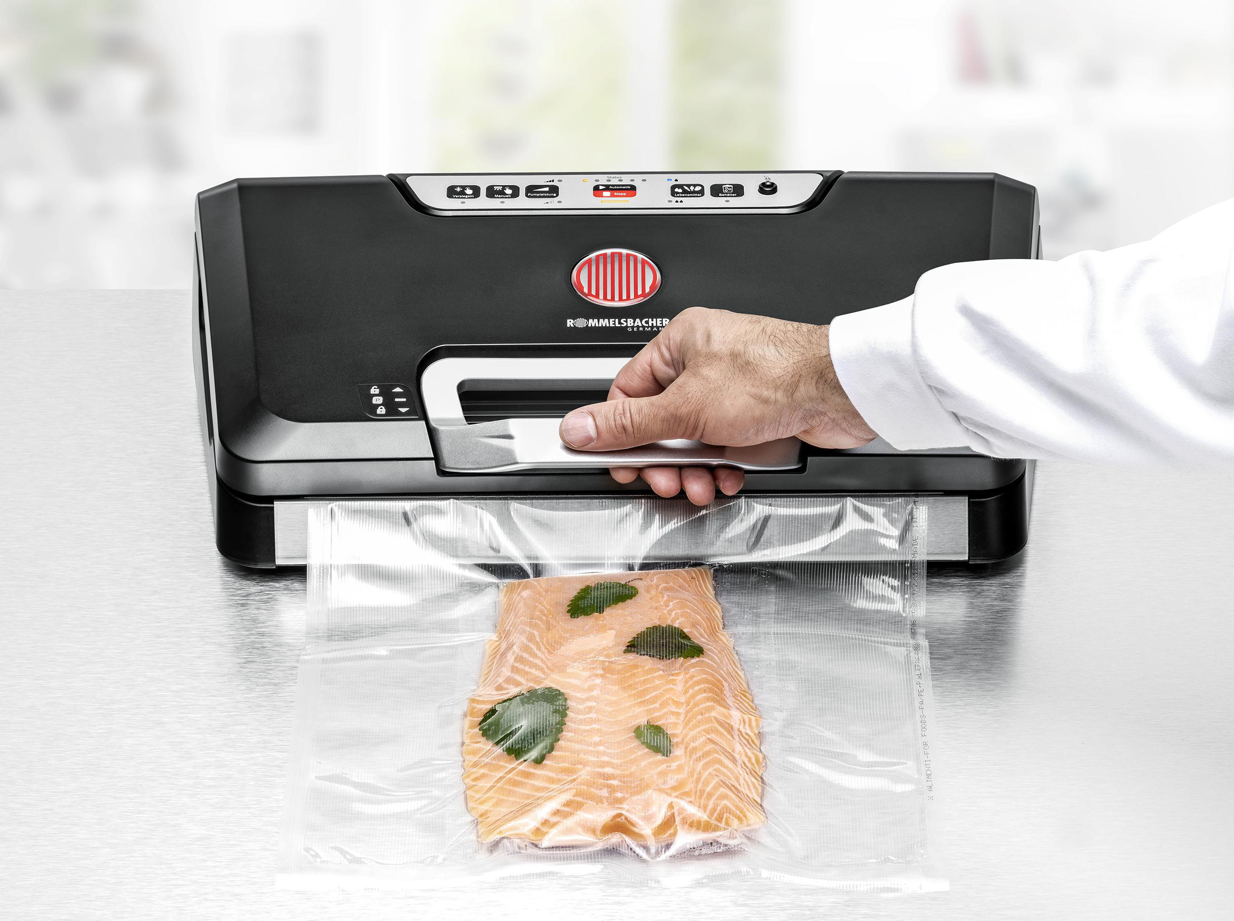 Mann versiegelt Lachs in einem Vakuumbeutel mit einem schwarzen Vakuumierer.