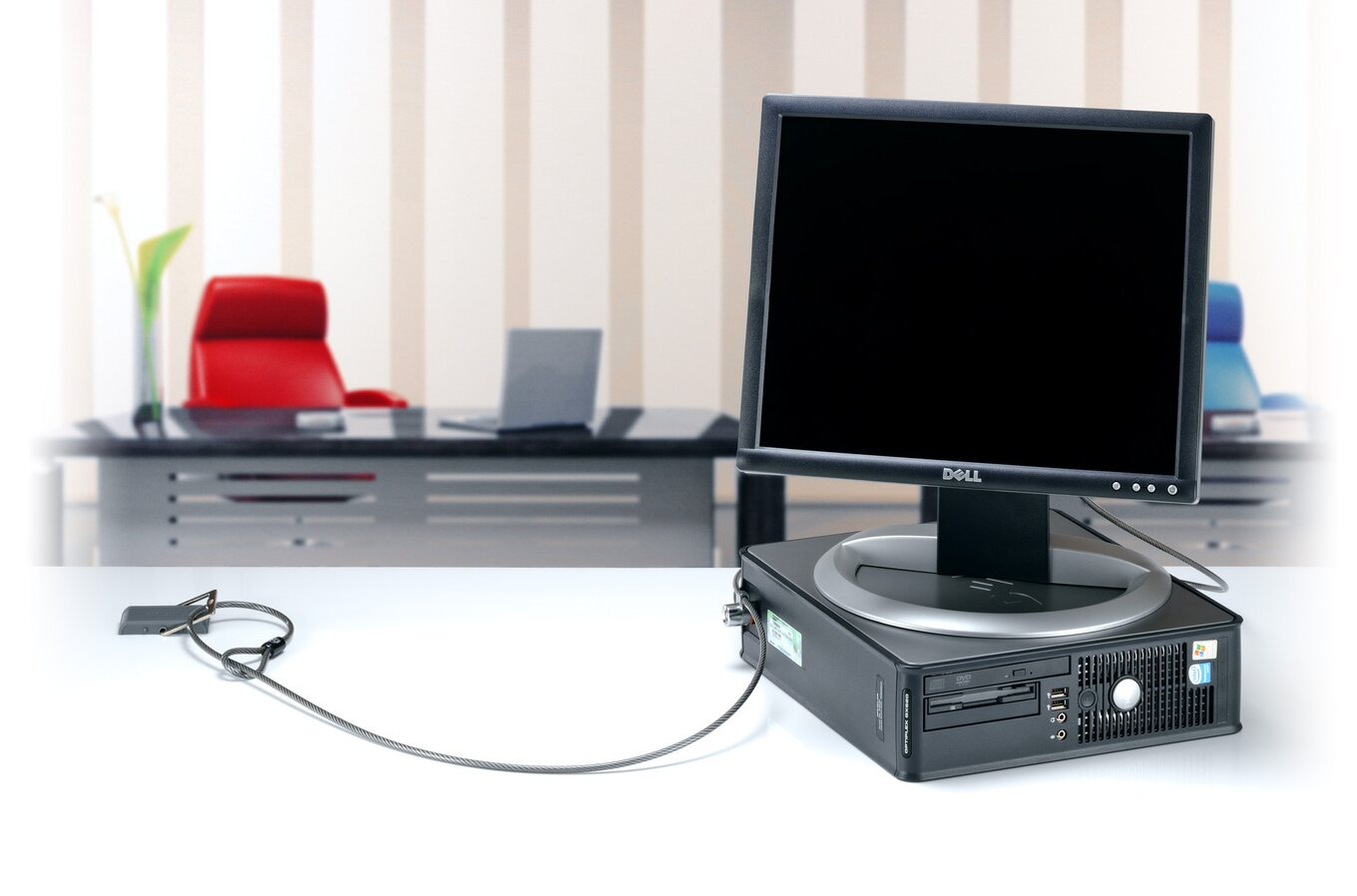Számítógép beállítása. Monitor, CPU, billentyűzet és biztonsági kábel. Fehér asztal, csíkos háttér.