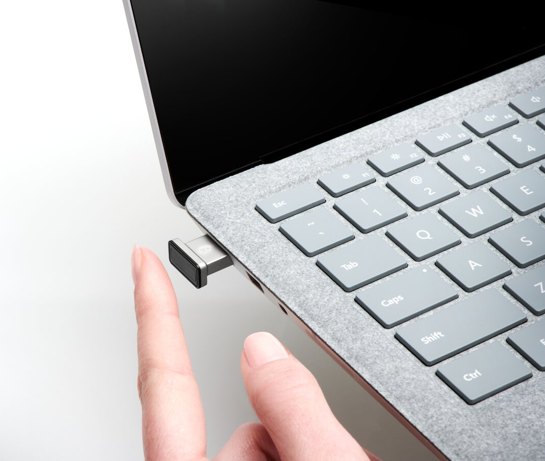 Egy személy keze, amint egy USB-meghajtót helyez a laptopba. A laptop szürke.