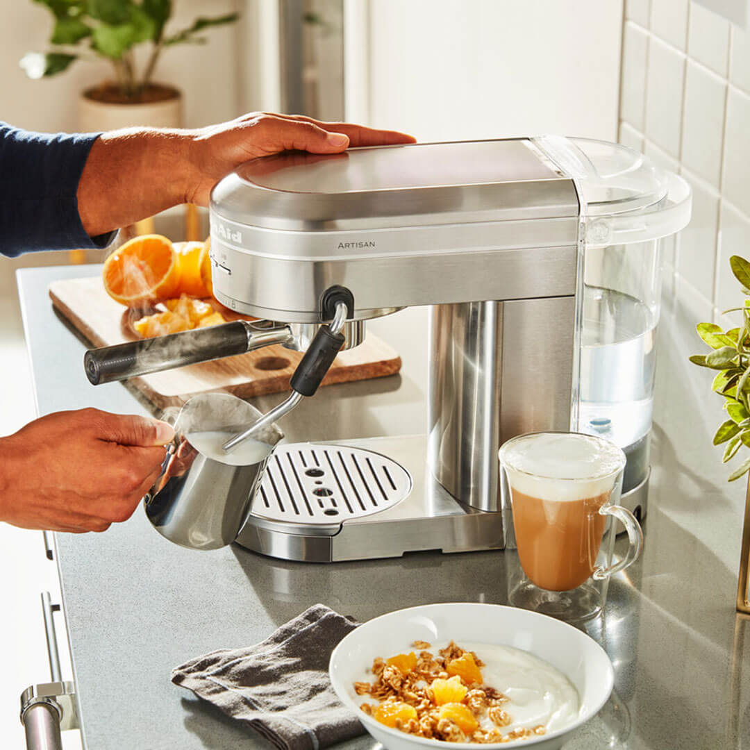 Egy személy kávét készít egy KitchenAid Artisan eszpresszó géppel. A tejet habosítják.
