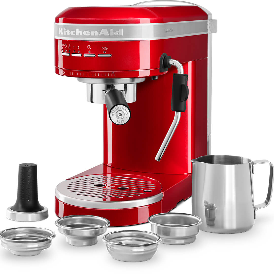 Piros KitchenAid eszpresszó gép rozsdamentes acél tartozékokkal és egy ezüst tejhabosító kancsóval.