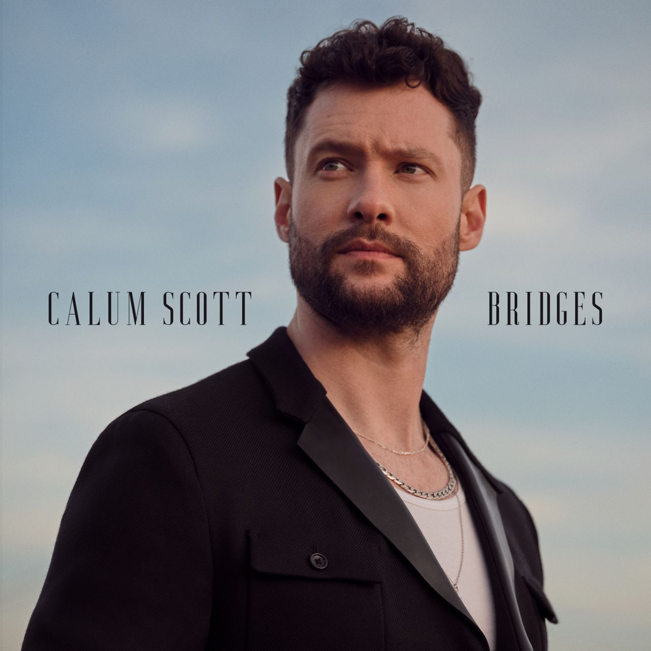 Calum Scott, trägt eine schwarze Jacke, schaut weg, mit dem Wort Bridges.