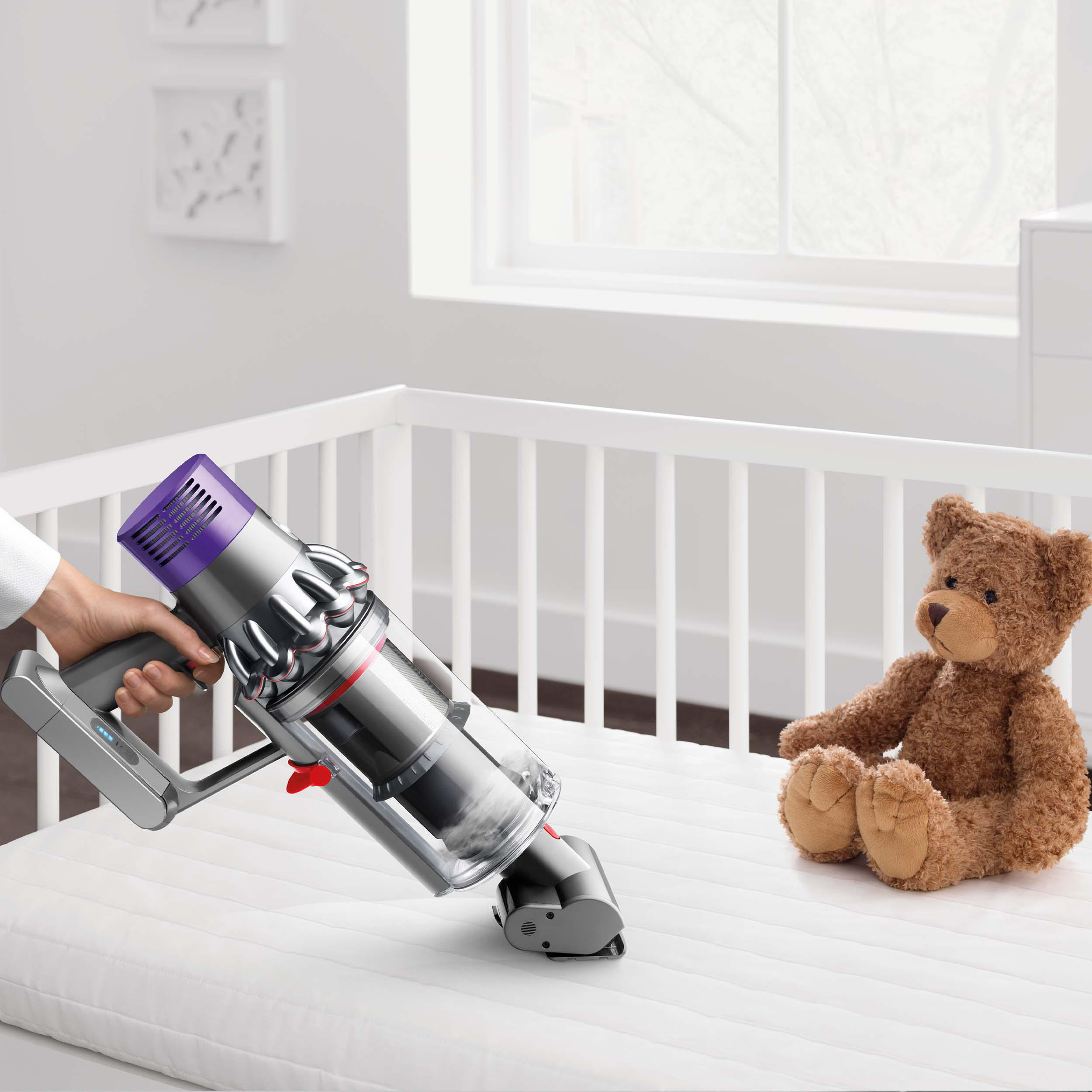 Person saugt Matratze mit Dyson. Teddybär sitzt daneben.