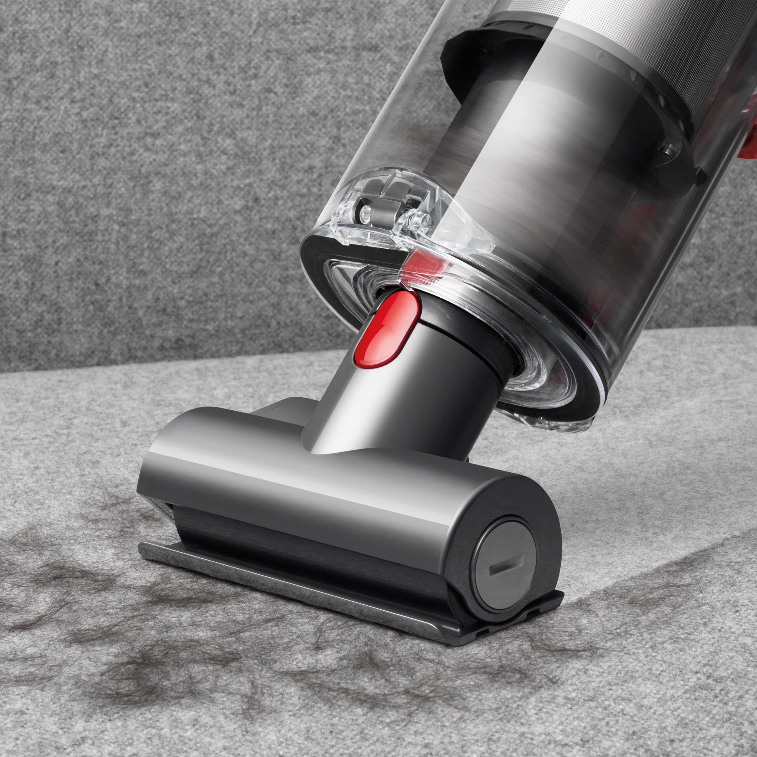 Staubsaugerkopf auf Teppich, entfernt Schmutz. Grauer Teppich und Dyson-Gerät.