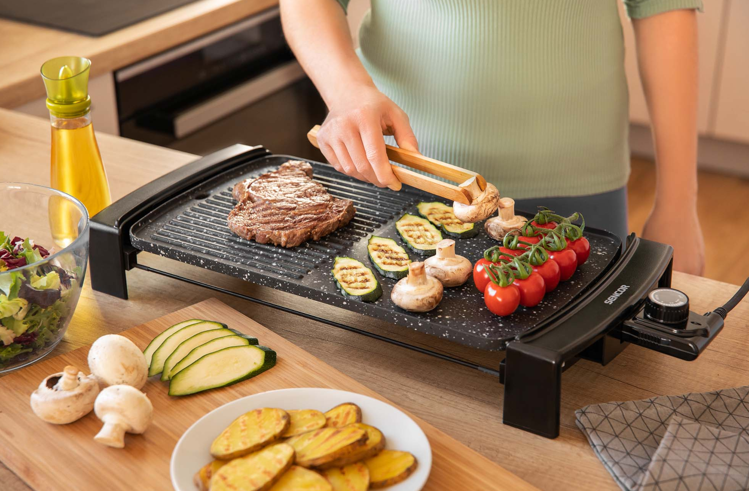 Grillezési beállítás: steak, zöldségek, olaj és fűszerek a pulton elhelyezett grillen.