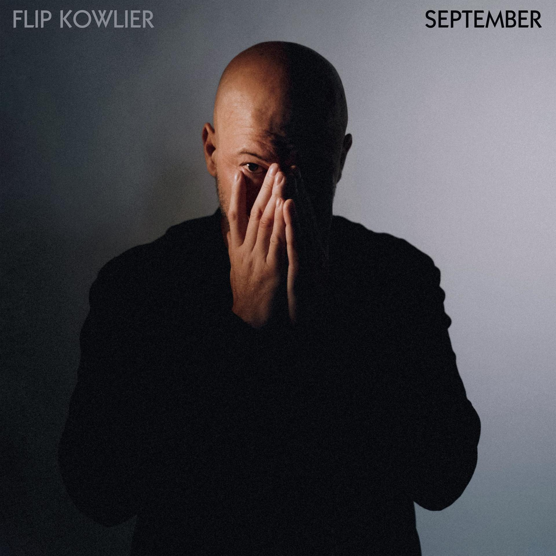 Albumhoes voor 'September'. Een man met een kale kop bedekt zijn gezicht met zijn handen.