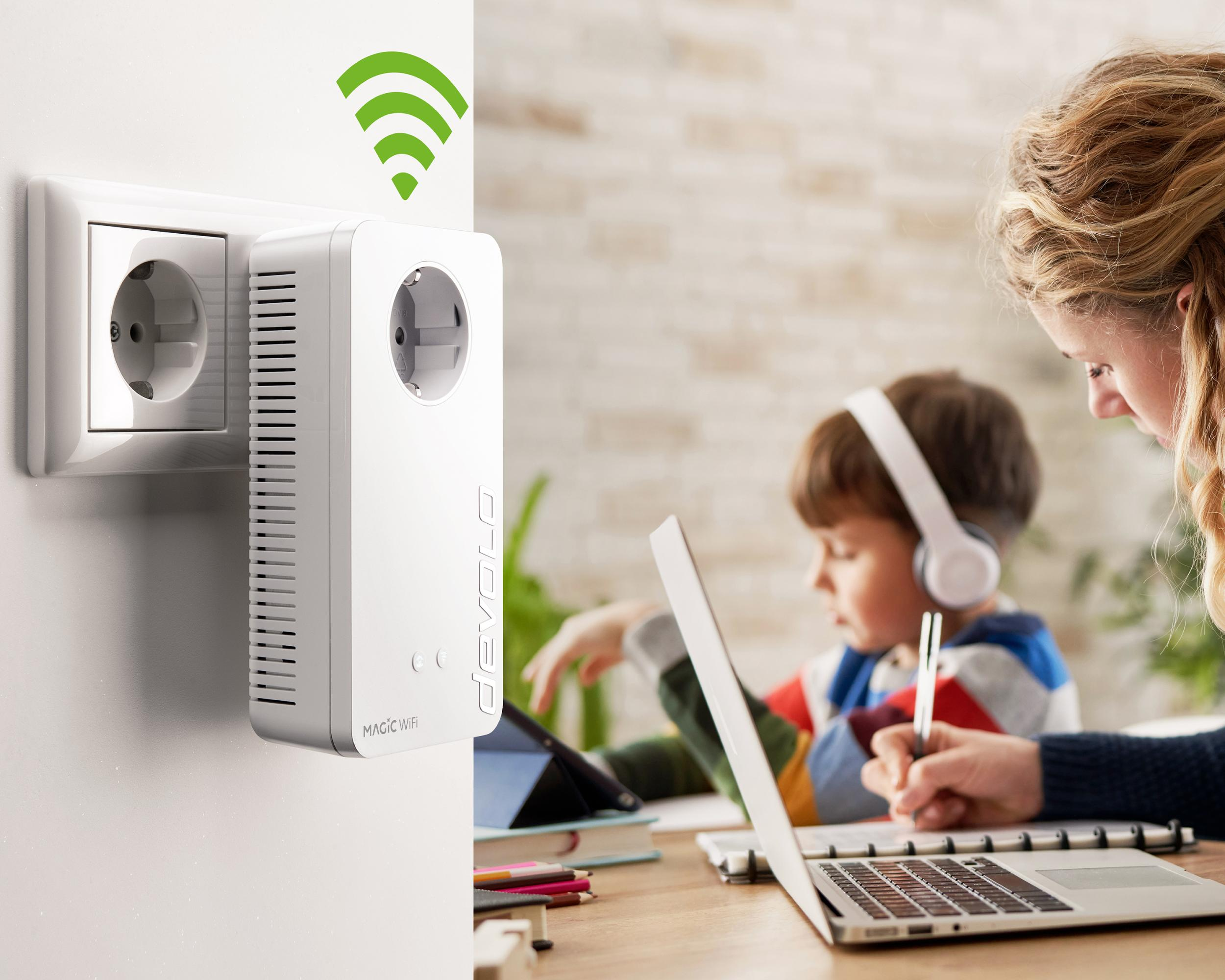 Ein weißer WLAN-Verlängerer, der in eine Steckdose gesteckt ist. Eine Frau und ein Kind arbeiten an einem Schreibtisch mit einem Laptop.