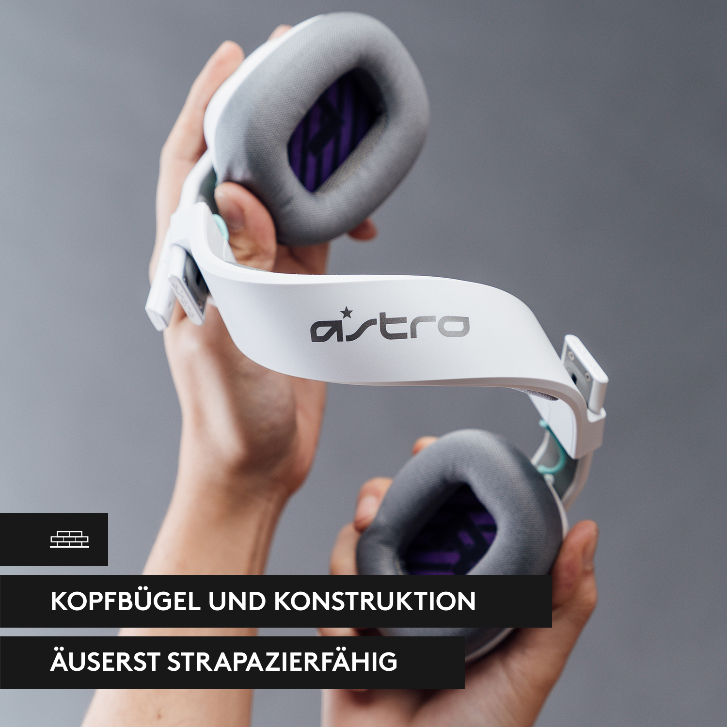 Weiß-graues Astro-Gaming-Headset in zwei Händen gehalten. Text auf dem Headset: 'astro'.