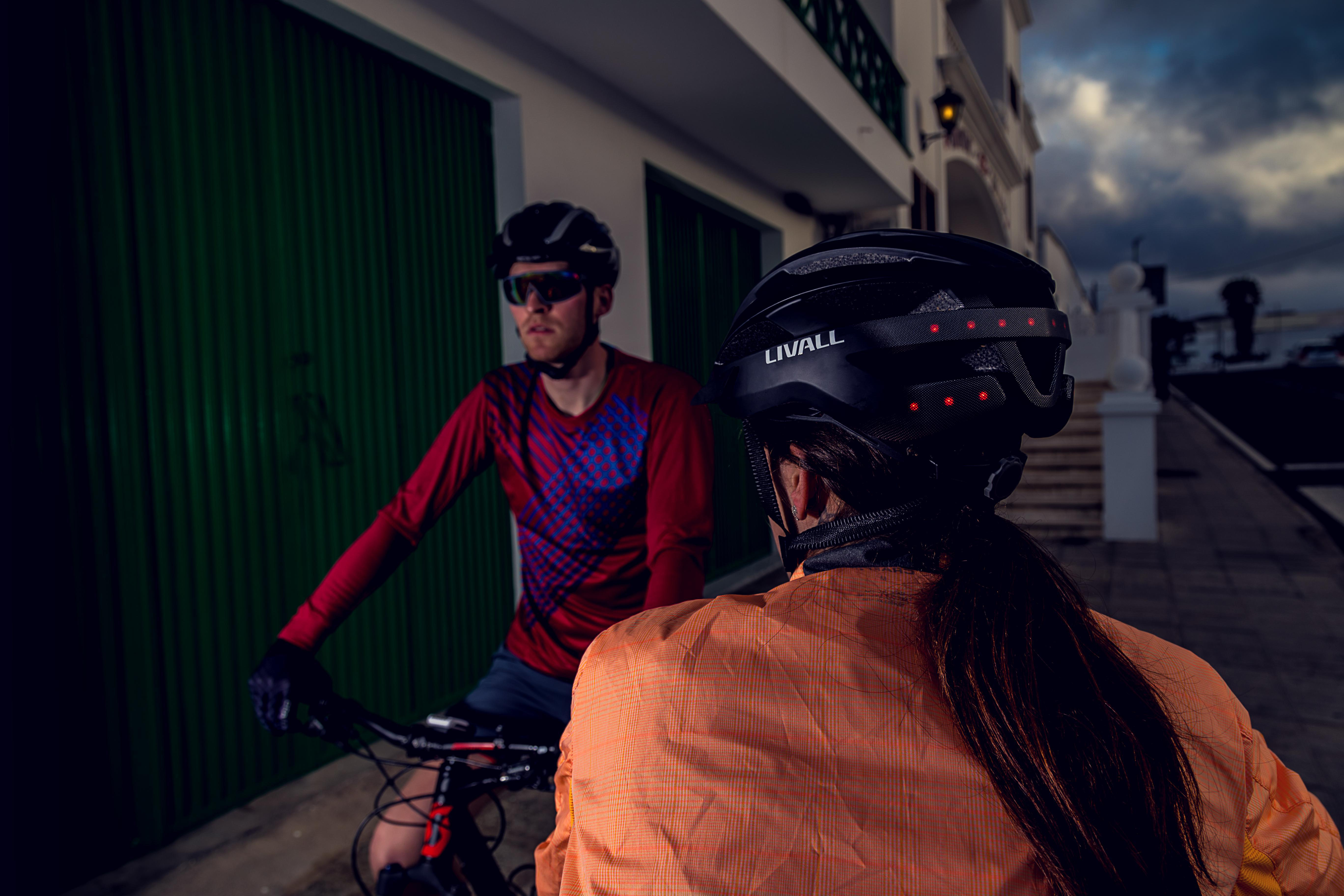 Zwei Radfahrer mit Helmen fahren auf einer Straße.