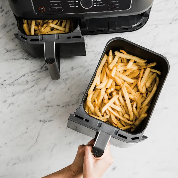 Friteuse à air avec deux paniers remplis de frites. Surface en marbre, vue aérienne.