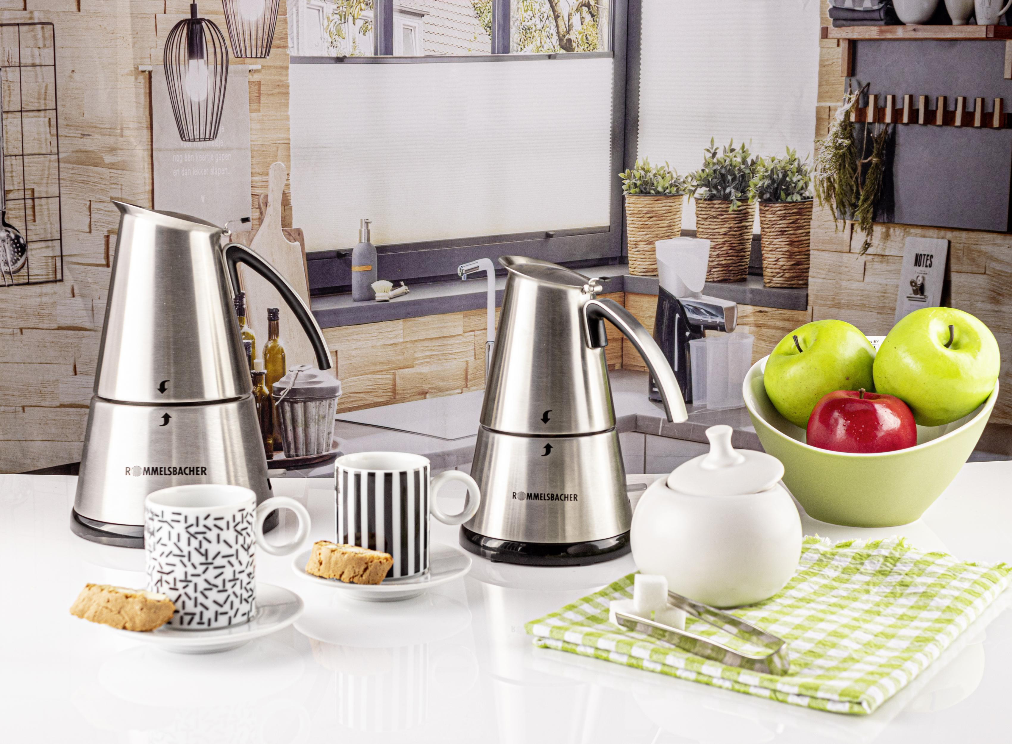 Drei silberne Kaffeemaschinen mit Kaffeetassen und einigen Keksen.