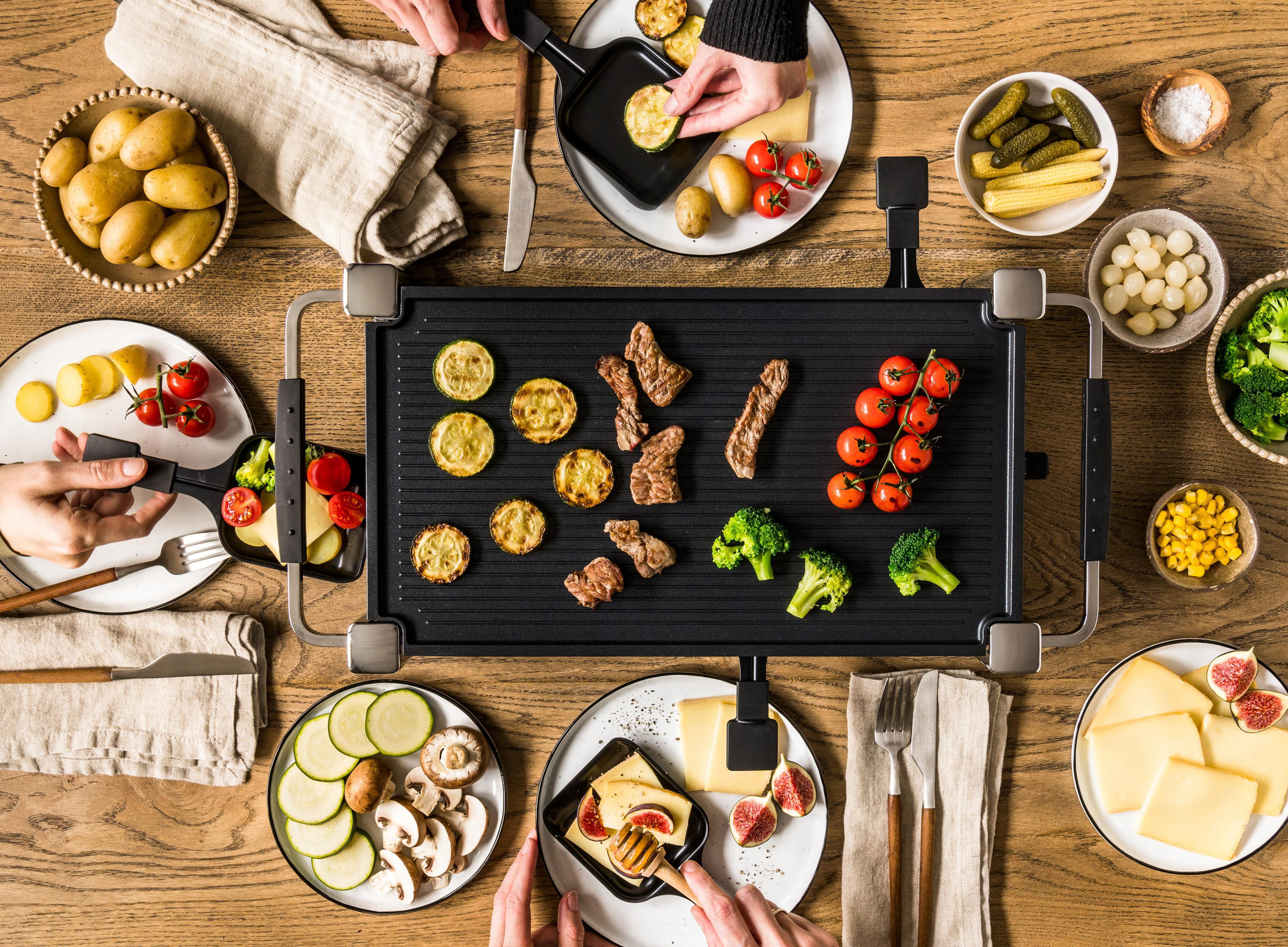 Eine Draufsicht auf eine Tischdekoration mit Essen und Händen von Personen.