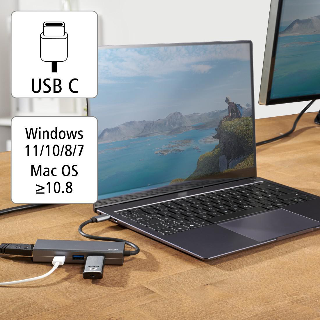 Ein USB-C-Hub verbindet sich mit einem Laptop, im Hintergrund befindet sich ein Monitor. Weiteres Zubehör liegt auf dem Tisch.