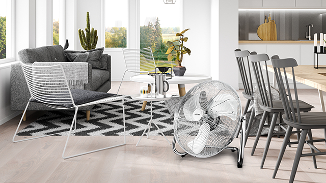 Modernes Wohnzimmer mit Ventilator, Stühlen und Tisch mit Dekoartikeln.
