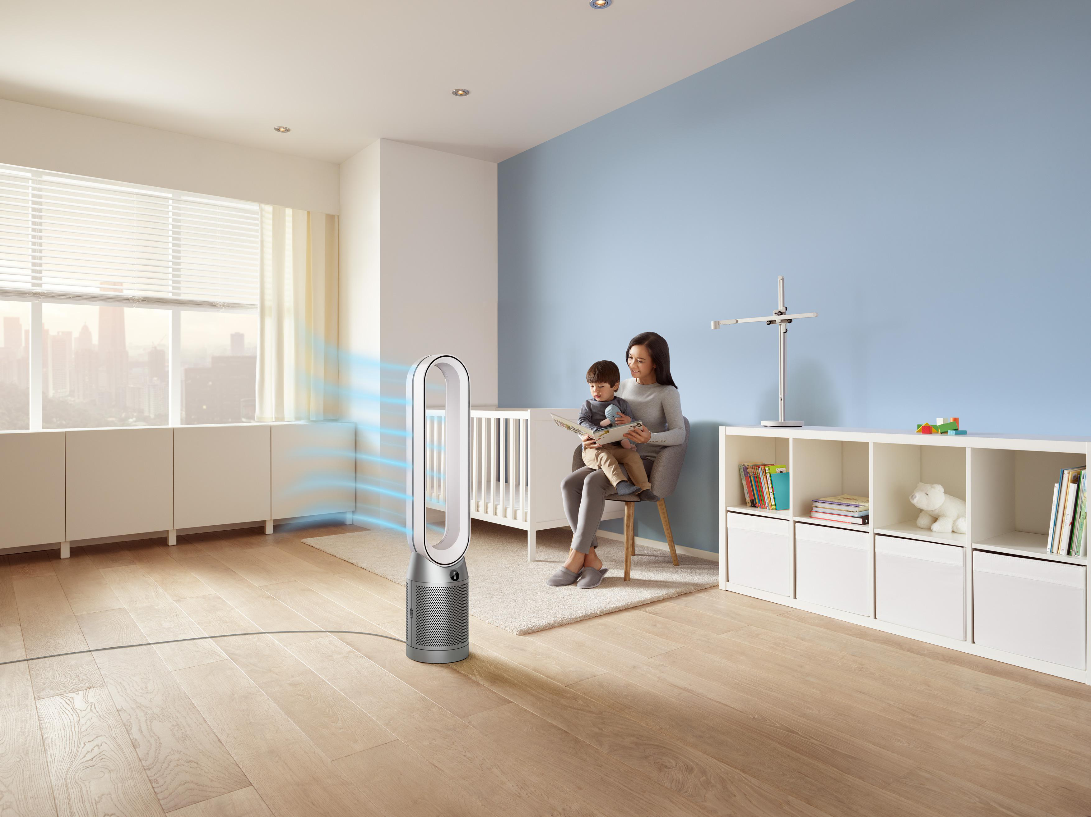 Eine Frau und ein Kind befinden sich in einem Raum mit einem Ventilator. Der Raum hat eine blaue Wand.