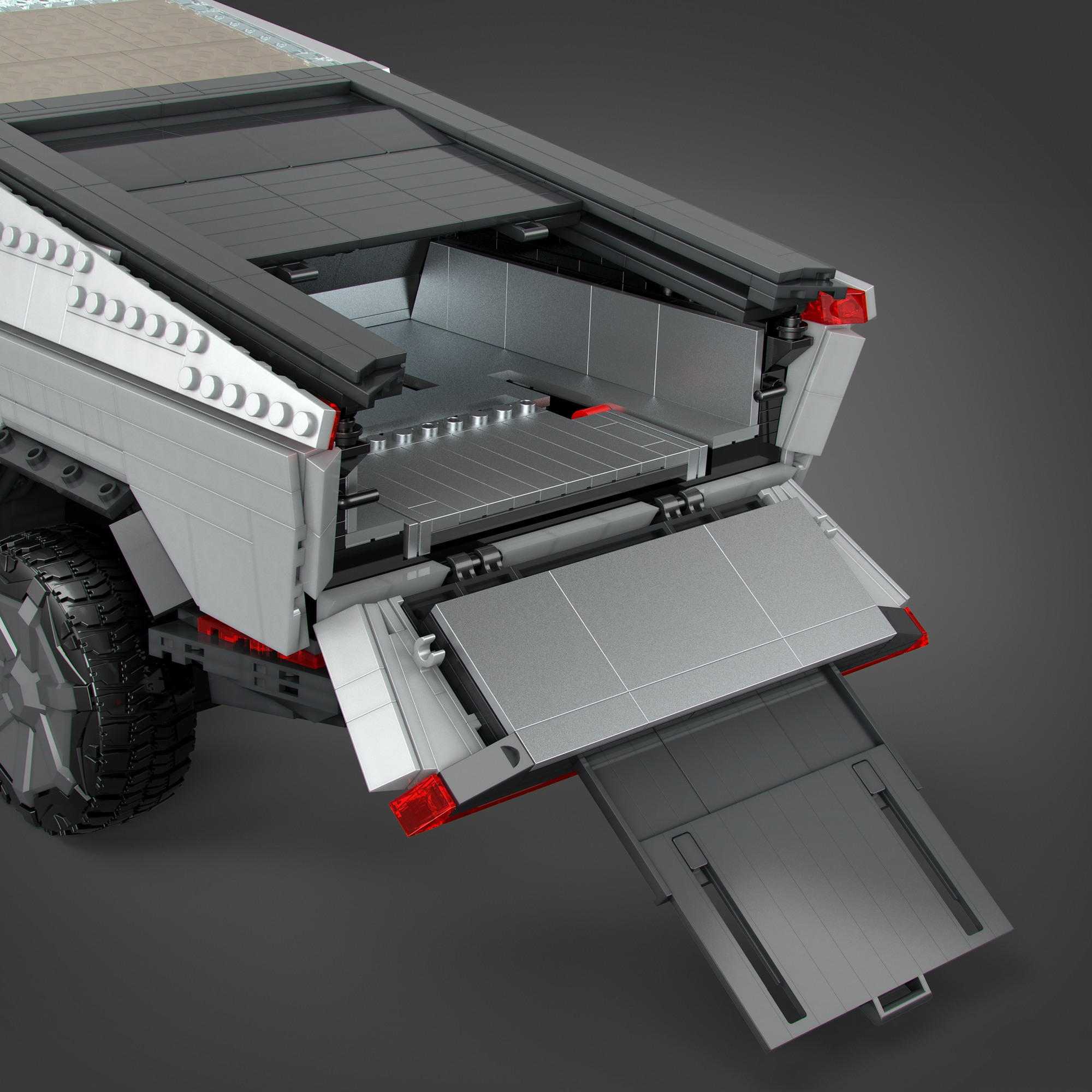 Ein Lego Cybertruck-Modell mit geöffneter Ladefläche. Der Truck ist silberfarben mit schwarzen Details, auf grauem Hintergrund.