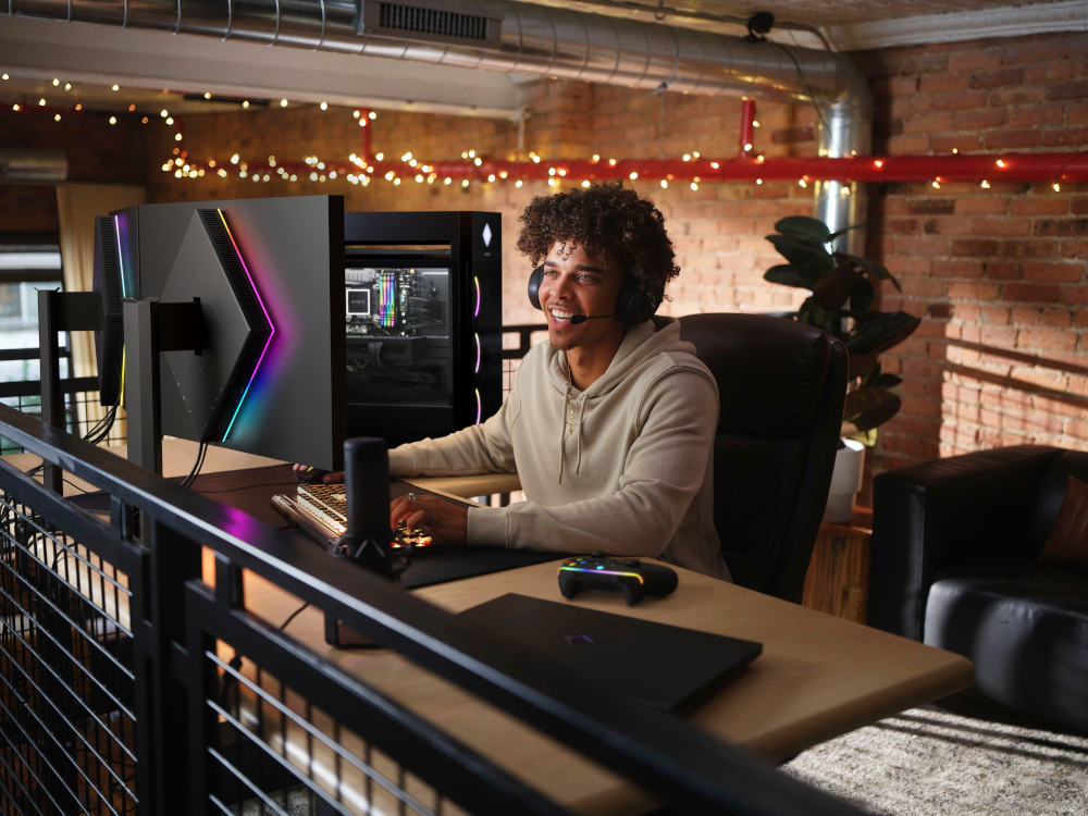 Een man zit aan een bureau te gamen. Hij heeft een headset op.