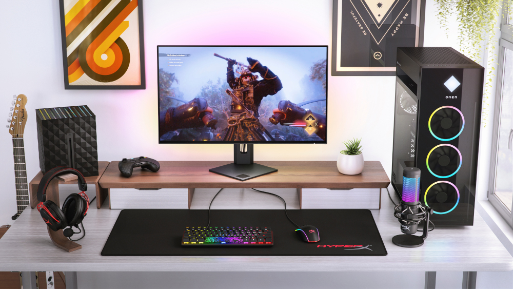 Een gaming-opstelling op een bureau: monitor, toetsenbord, muis, microfoon, luidsprekers en gitaar.