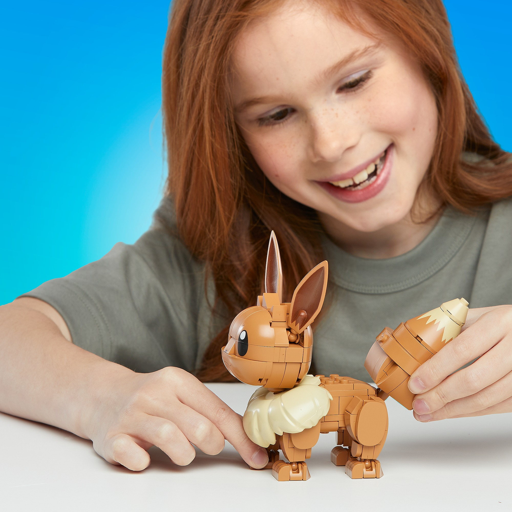 Ein Mädchen spielt mit einem Lego-Modell von Evoli, einem braunen Pokémon-Charakter.