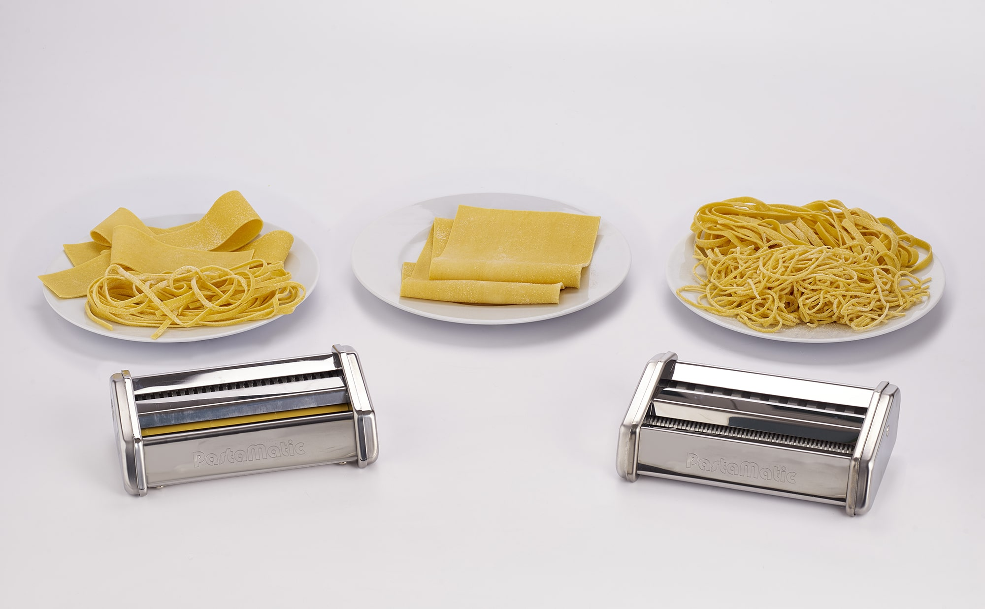 Strumenti per fare la pasta. Tre piatti con diversi tipi di pasta e due macchine per la pasta.