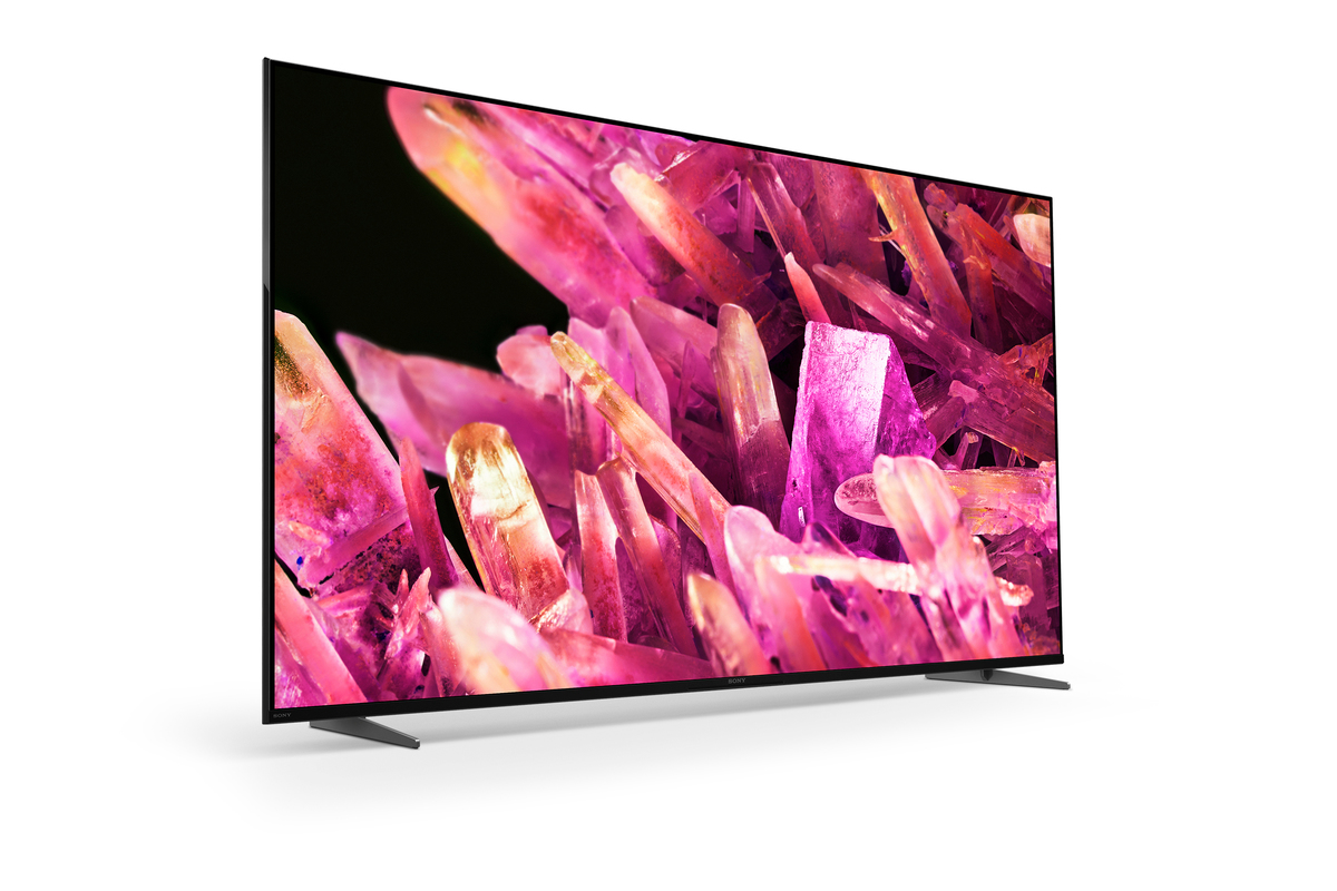 Un televisor moderno de pantalla plana con marco negro, mostrando una imagen abstracta vibrante en rosa y morado.