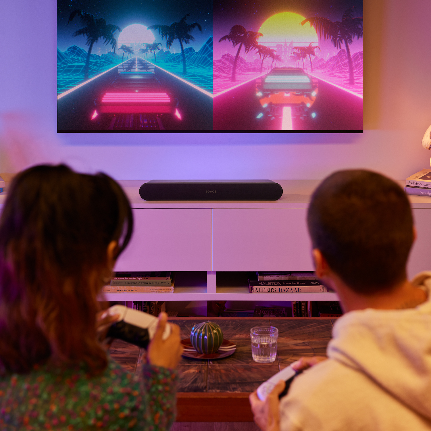 Twee mensen spelen videogames op een bank. Een tv toont spelgraphics.