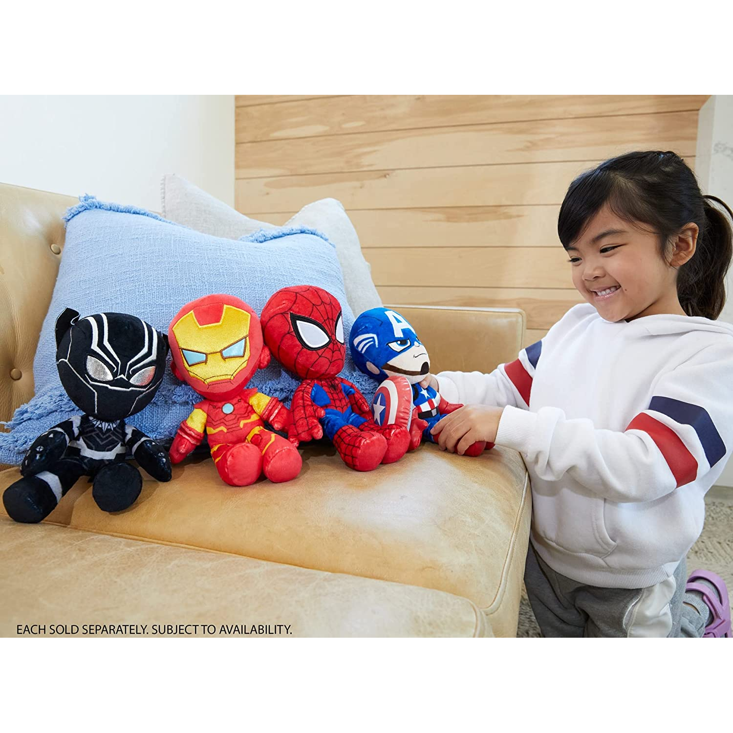 Niña con peluches de personajes Marvel sentada en un sofá.