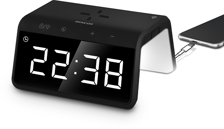 Fekete digitális ébresztőóra 22:38-at mutat. Egy telefon csatlakozik az oldalán.