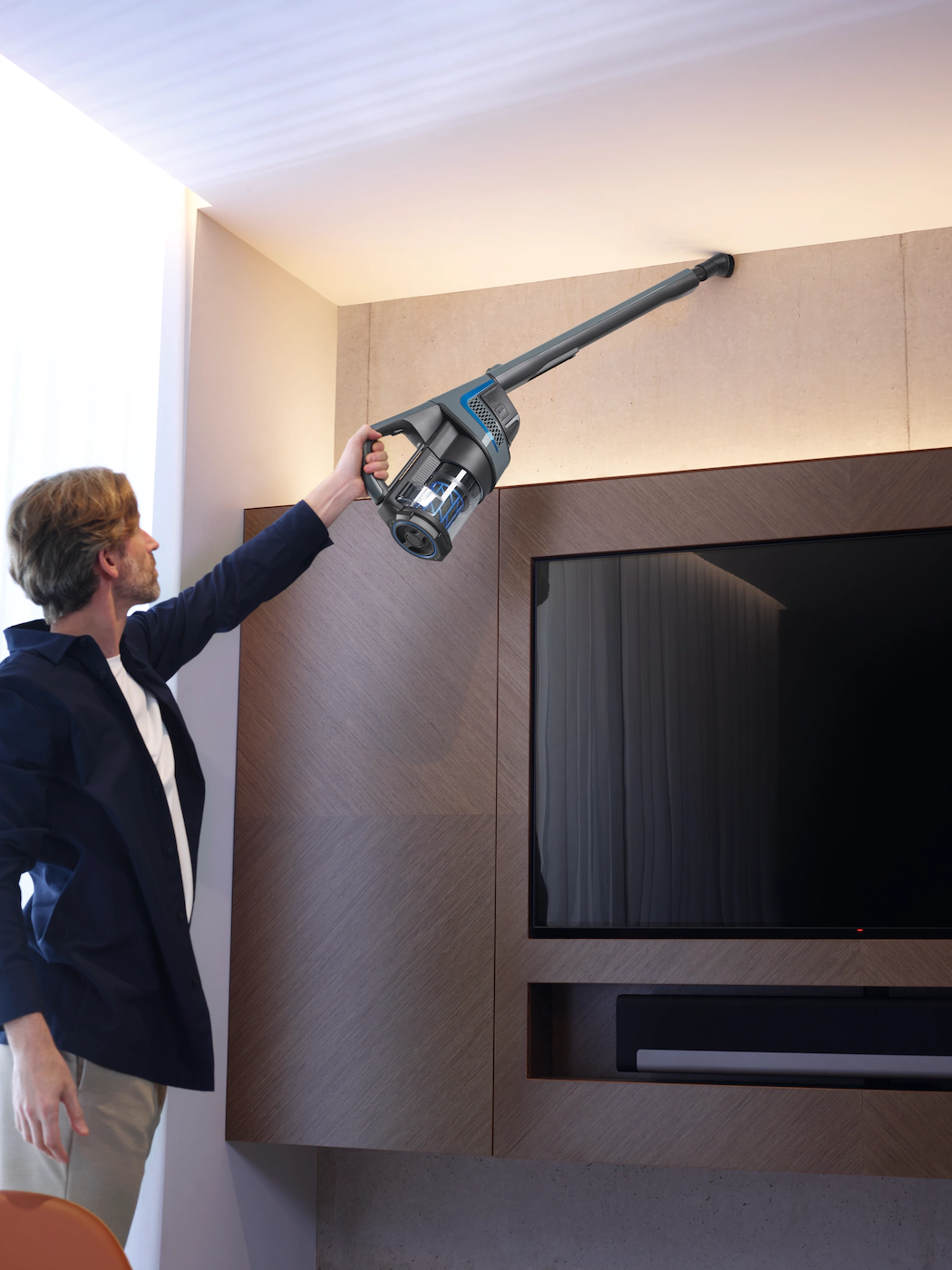 Un homme passe l'aspirateur au plafond avec un aspirateur à main.