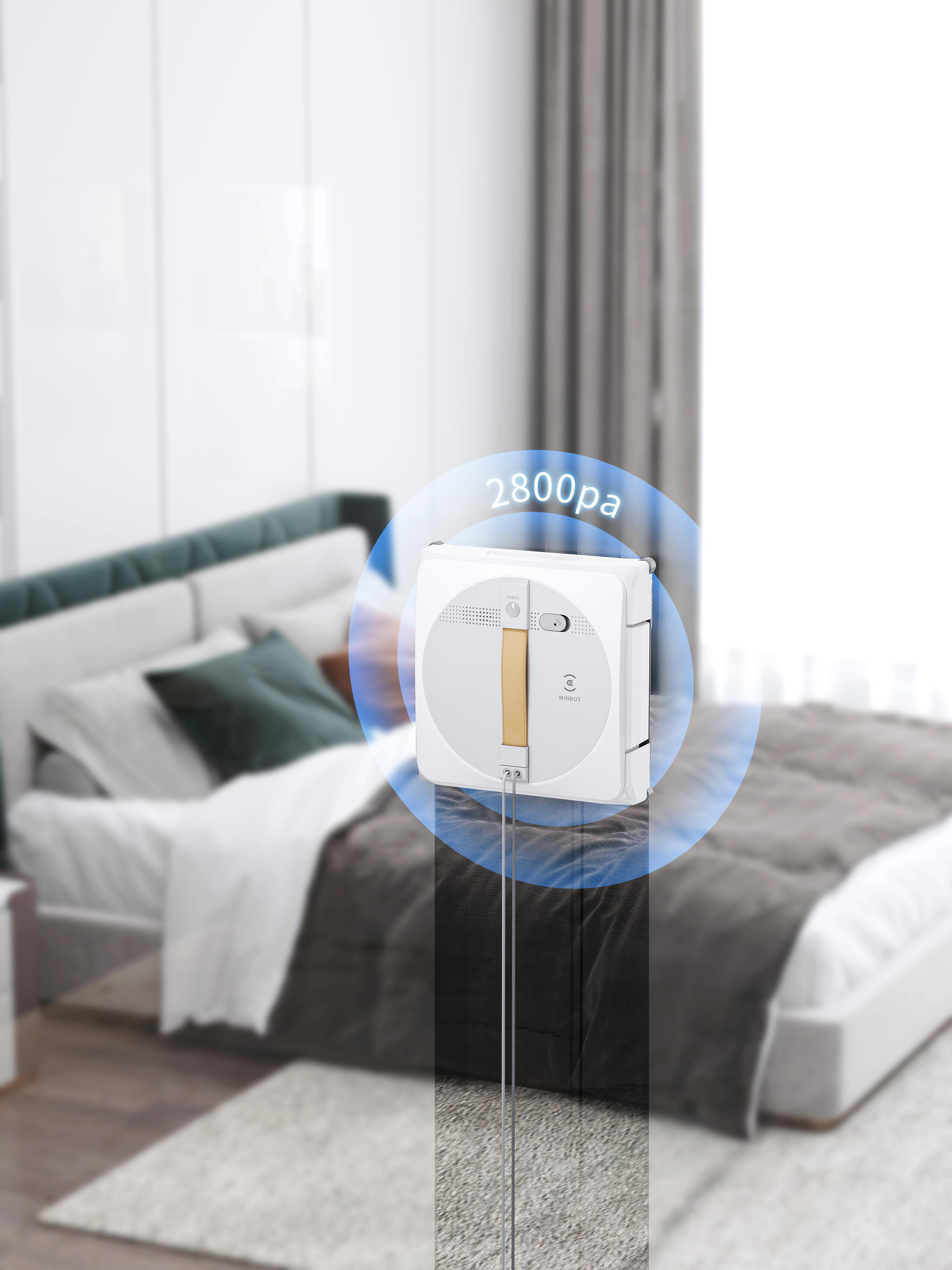 Ein Fensterputzroboter liegt auf einem Bett. Es ist rund und weiß. Die Saugkraft beträgt 2800 Pa.