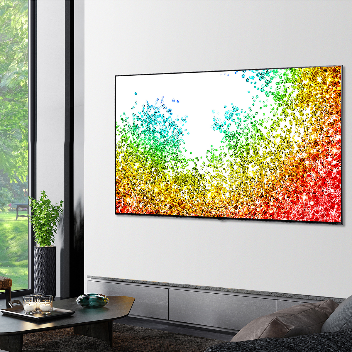 Una gran pantalla de TV que muestra formas coloridas, montada en una pared blanca sobre un gabinete gris.
