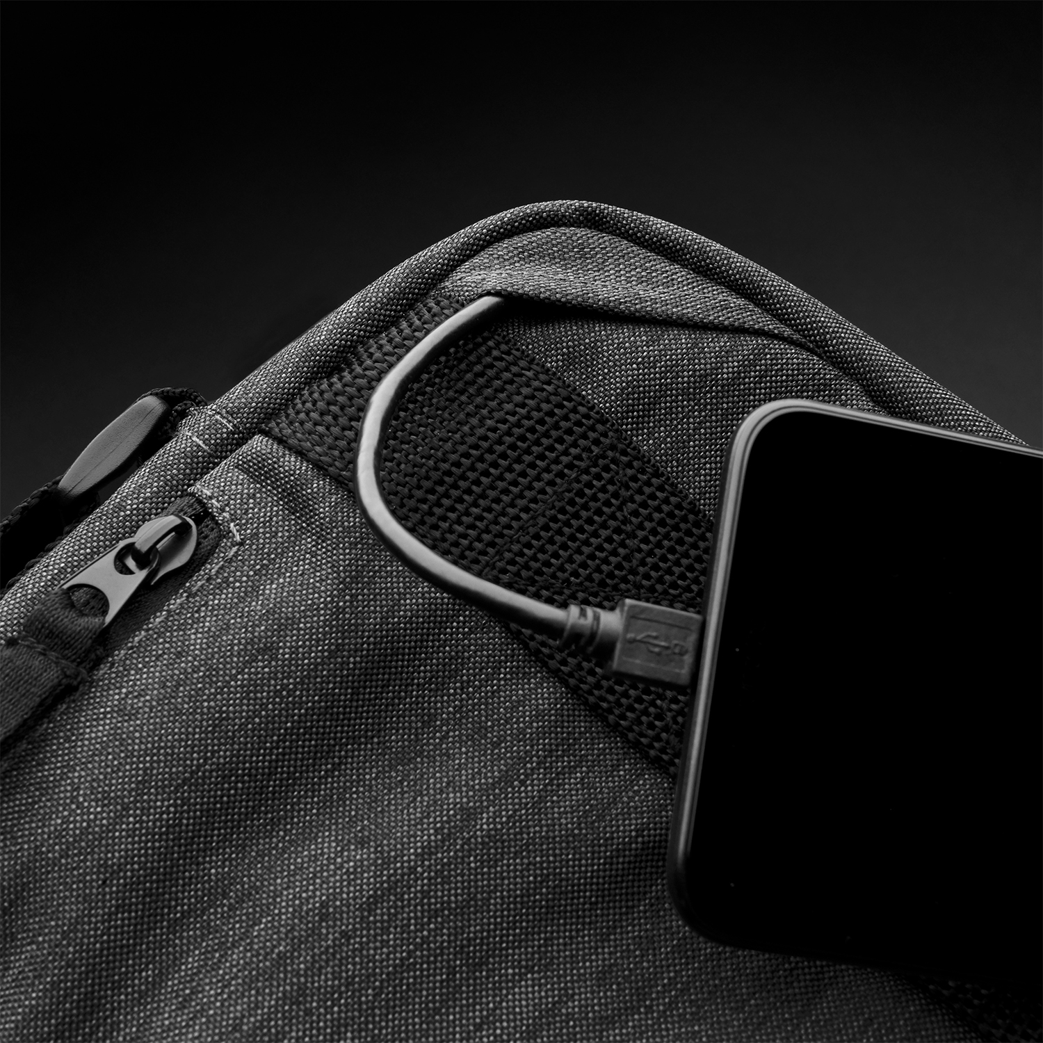 Borsa nera con cavo USB collegato e smartphone.