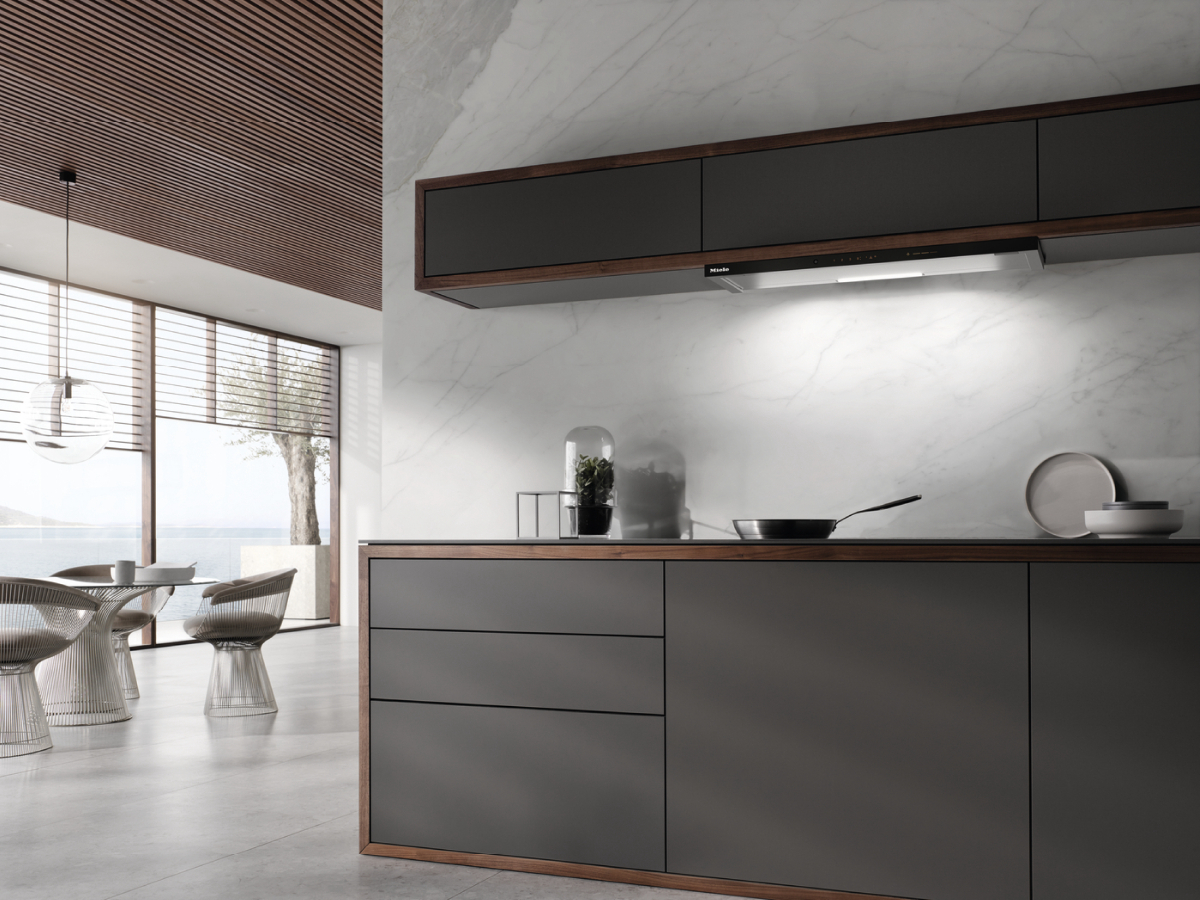 Modernes Kücheninterieur mit dunkelgrauen Schränken, Holzakzenten und großen Fenstern.