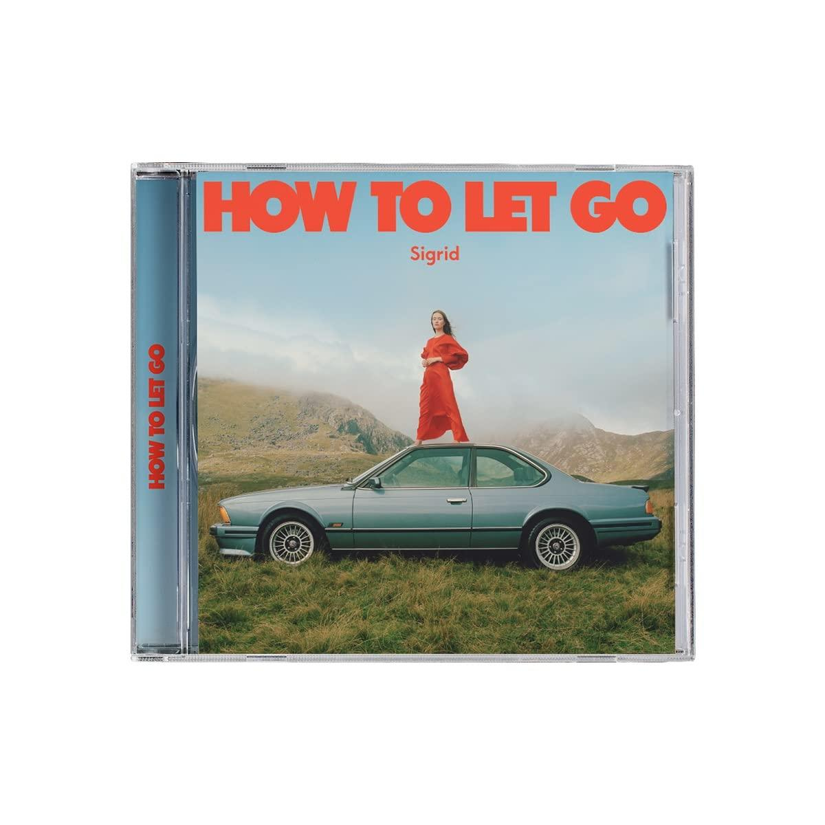 CD-Hülle mit Sigrids Albumcover "HOW TO LET GO". Frau in Rot auf Auto im Feld.