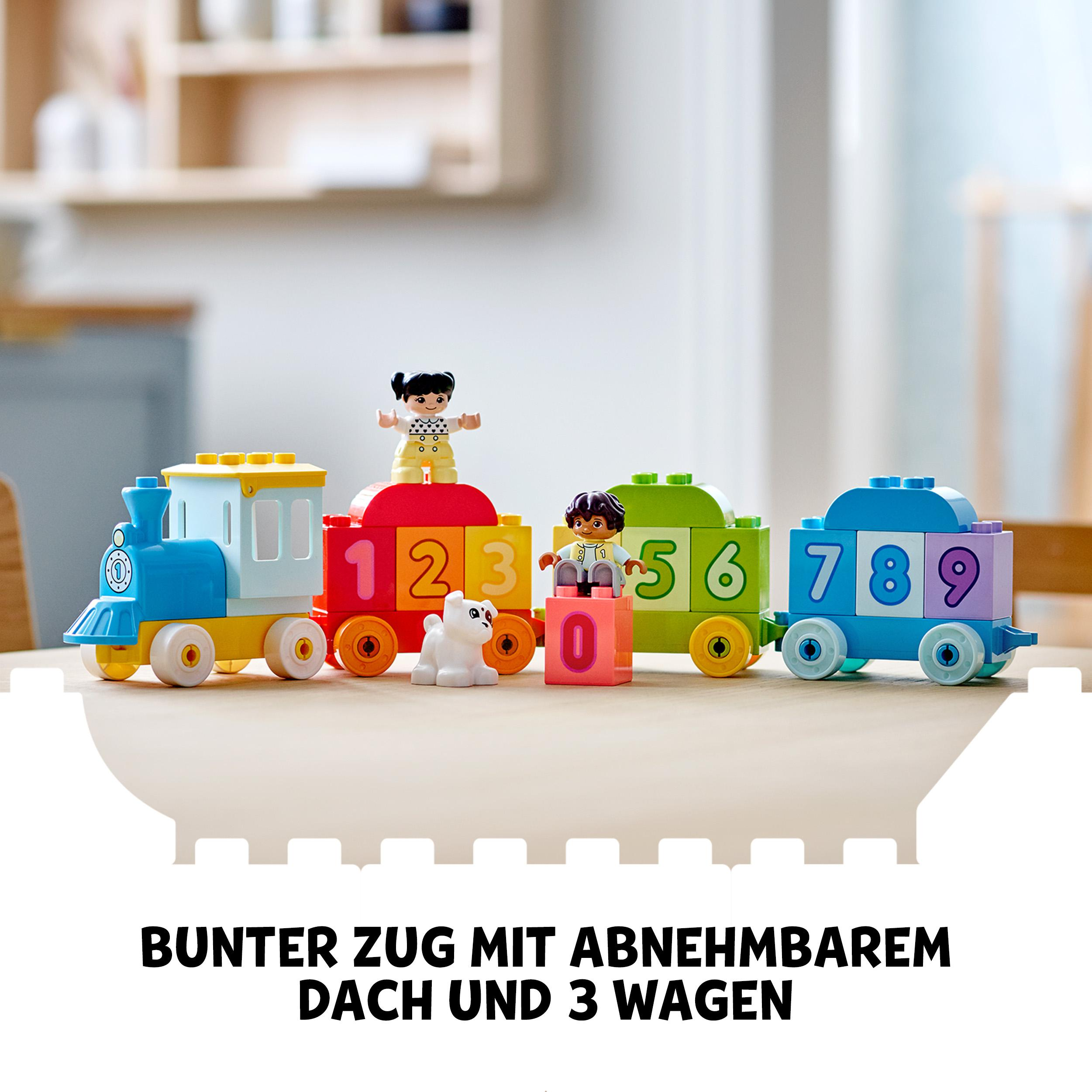 Ein bunter Spielzeugzug mit abnehmbarem Dach und 3 Wagen auf einem Tisch.