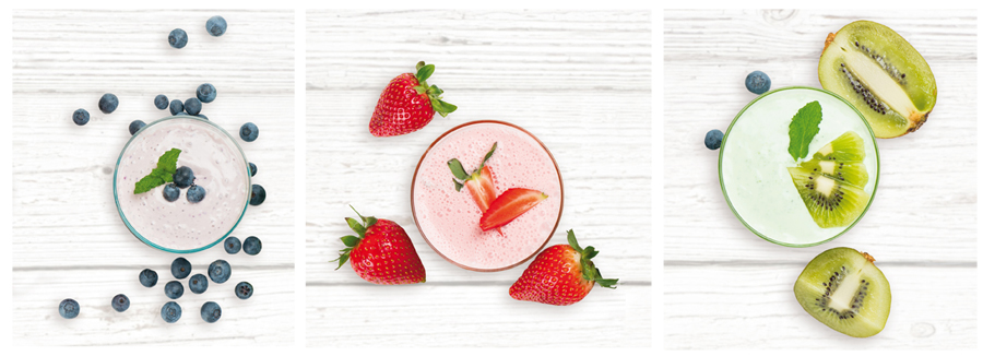Három smoothie bogyókkal, eperrel és kivivel, fehér fa felületen. Mentalevéllel a tetején.
