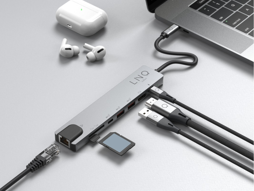 Hub USB argenté avec divers ports, connecté à un ordinateur portable et à d'autres appareils. Carte SD insérée.