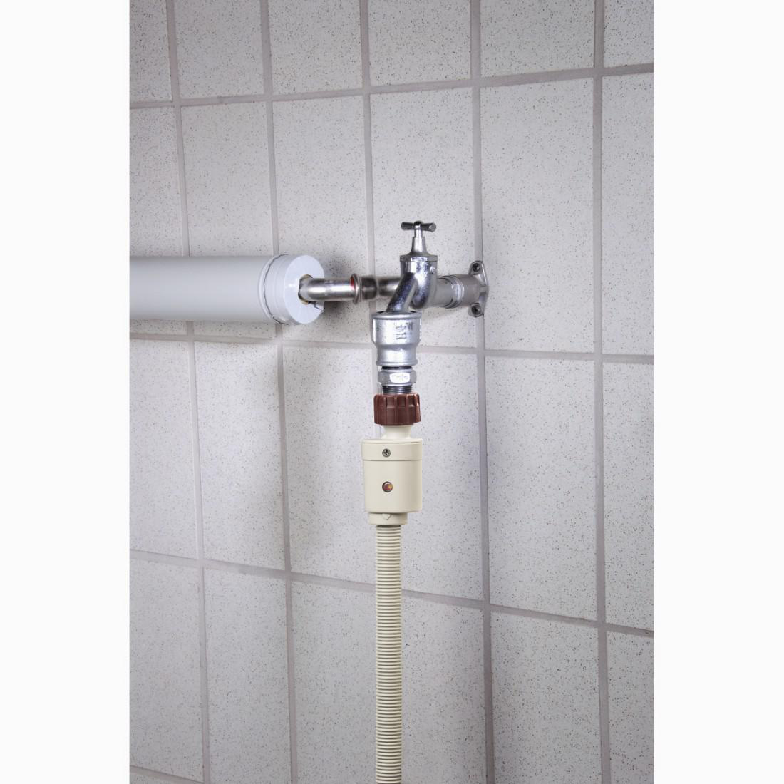 Wasserhahn an einem Schlauch mit weißem Fliesen Hintergrund.