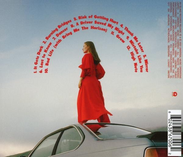 Frau in rotem Kleid auf einem Auto. Regenbogenbogen mit Songtiteln am Himmel.