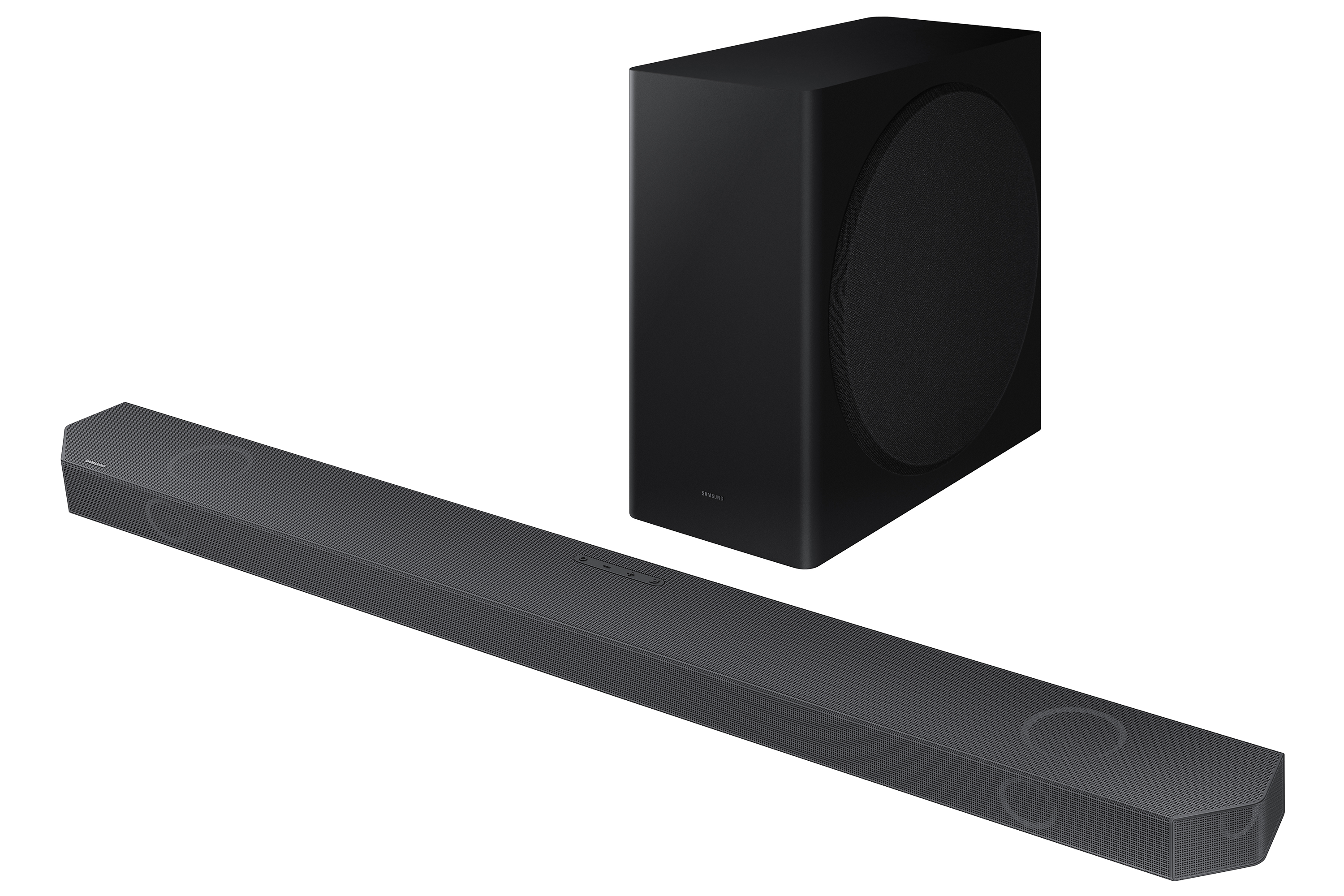Una barra de sonido y un subwoofer negros. La barra es larga, el subwoofer rectangular. Ambos están en una superficie oscura.