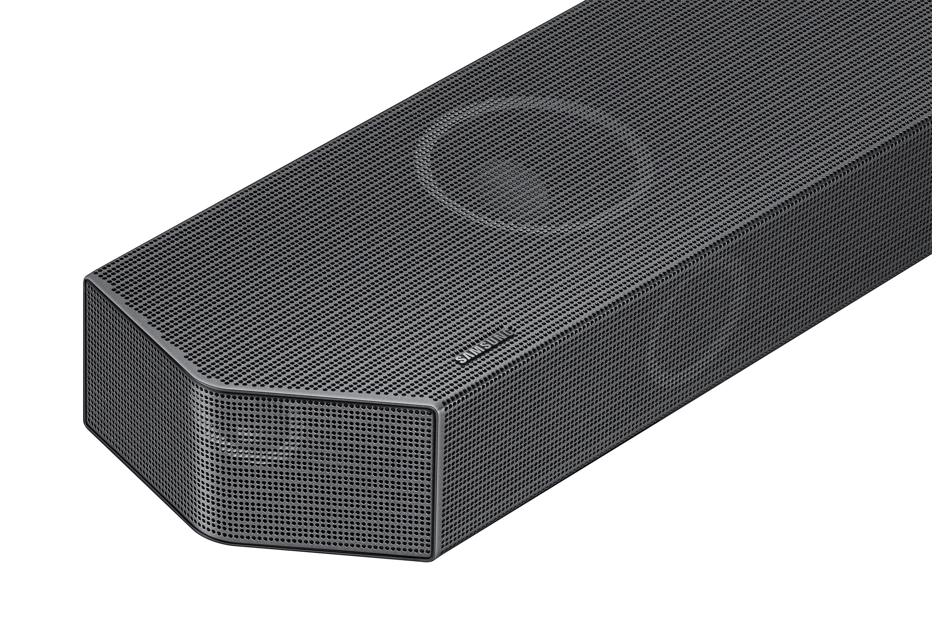 Barra de sonido negra con superficie perforada. Logotipo de Samsung. Vista en ángulo sobre fondo negro.