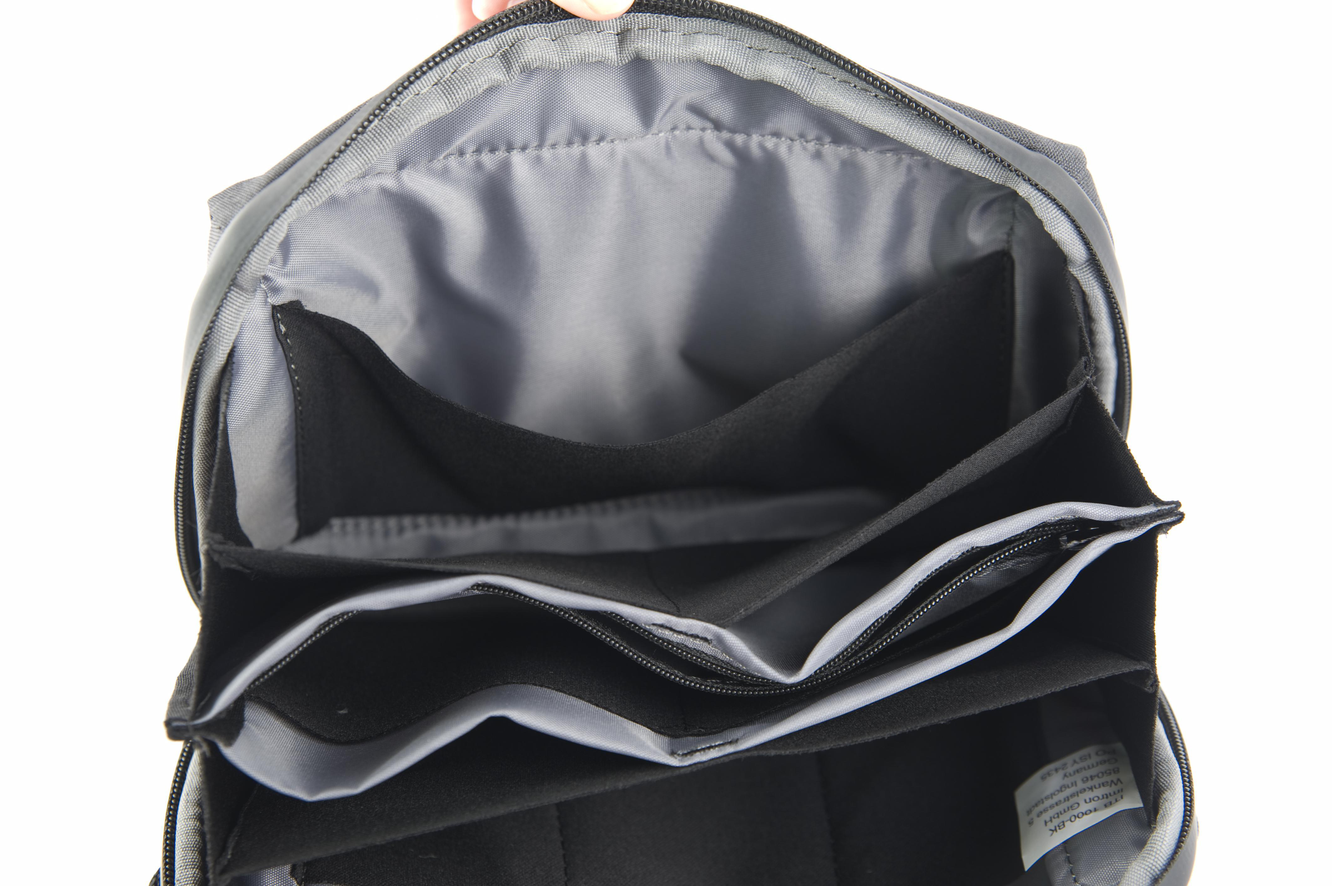Offene schwarze Tasche mit mehreren Taschen. Grauer Innenraum, einige Taschen mit Reißverschlüssen.
