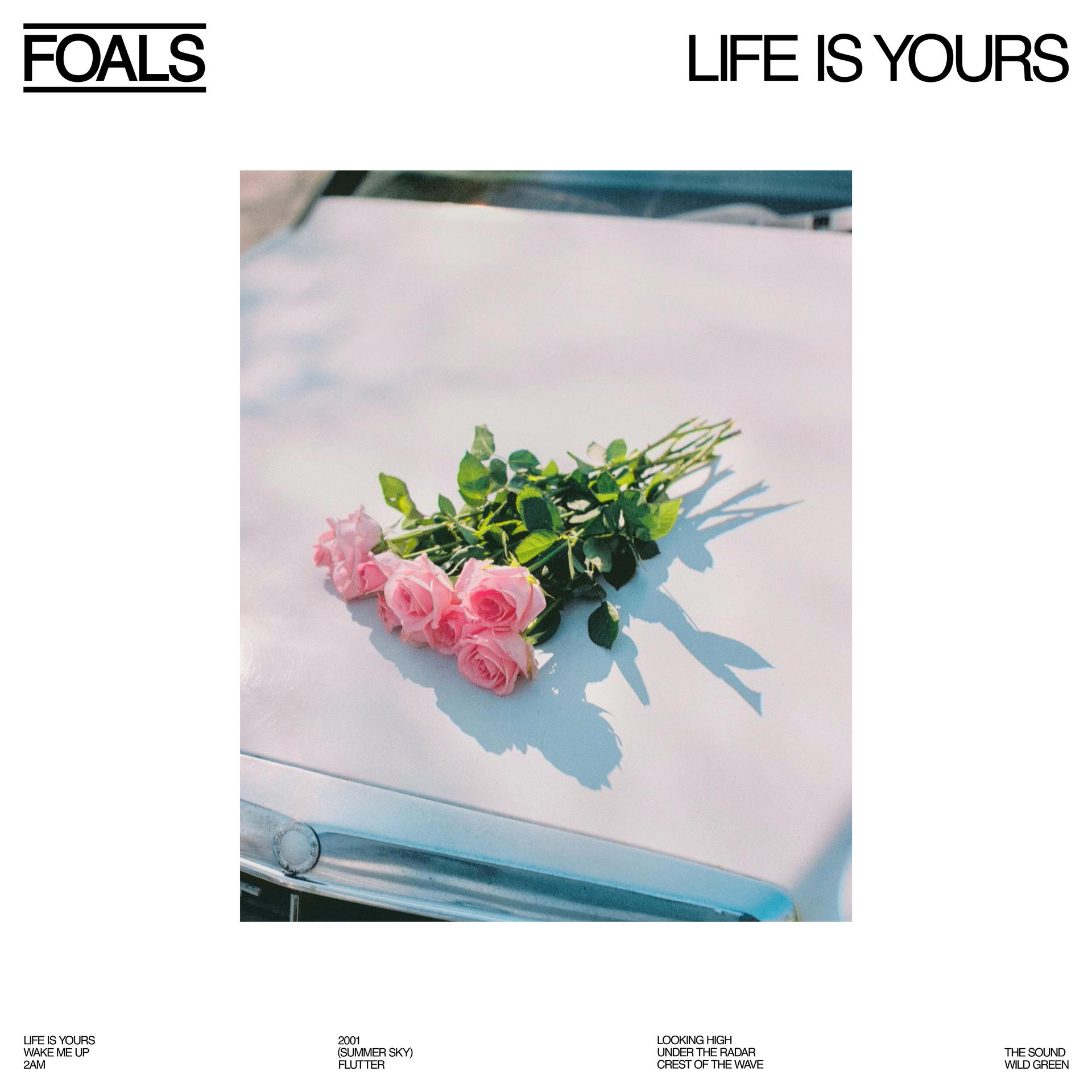 Pochette de l'album Foals avec des roses roses sur une voiture blanche. Le texte dit Life Is Yours.