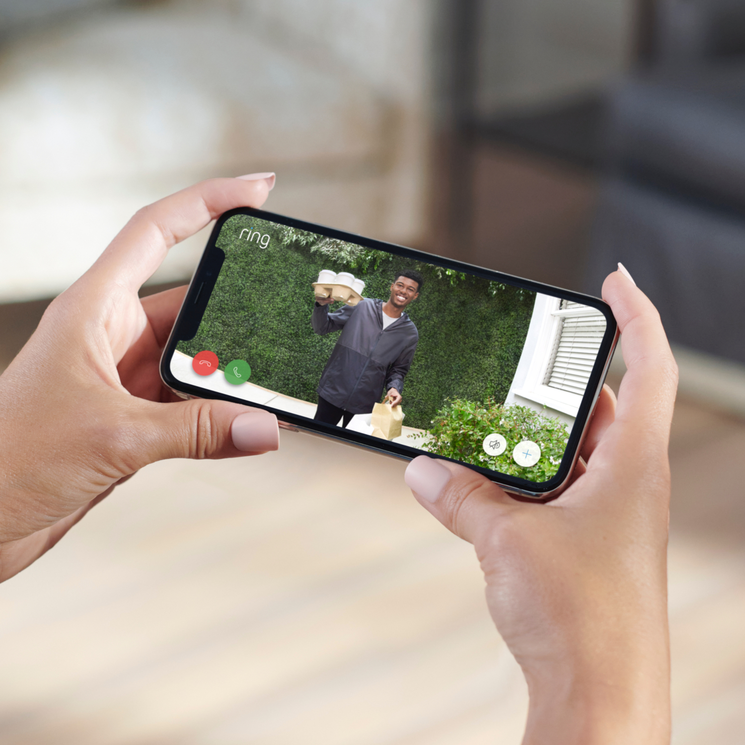 A person holding a phone showing a delivery person at the door.