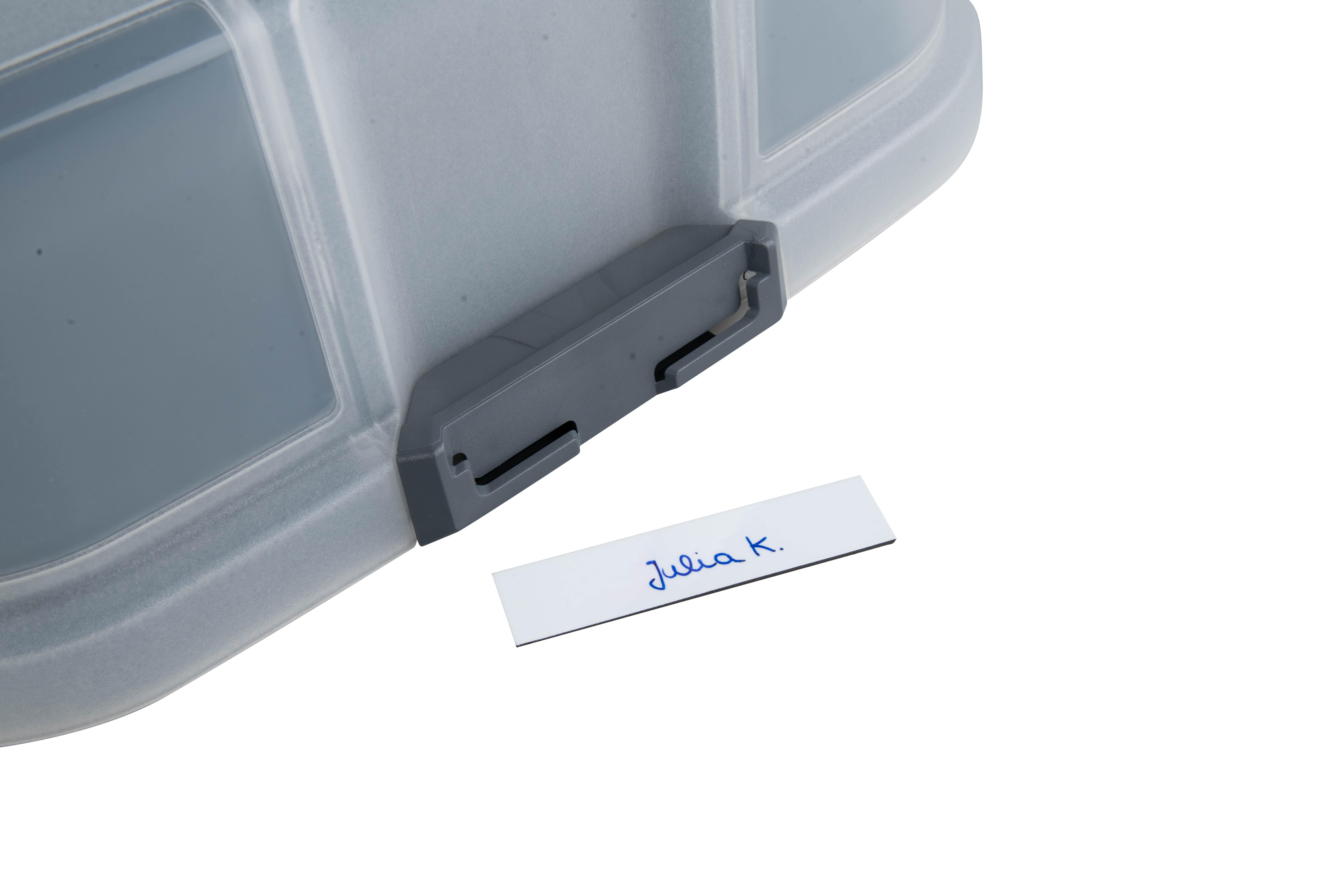 Ein Plastikbehälter mit dem Etikett 'Julia K.' liegt auf einer weißen Oberfläche.
